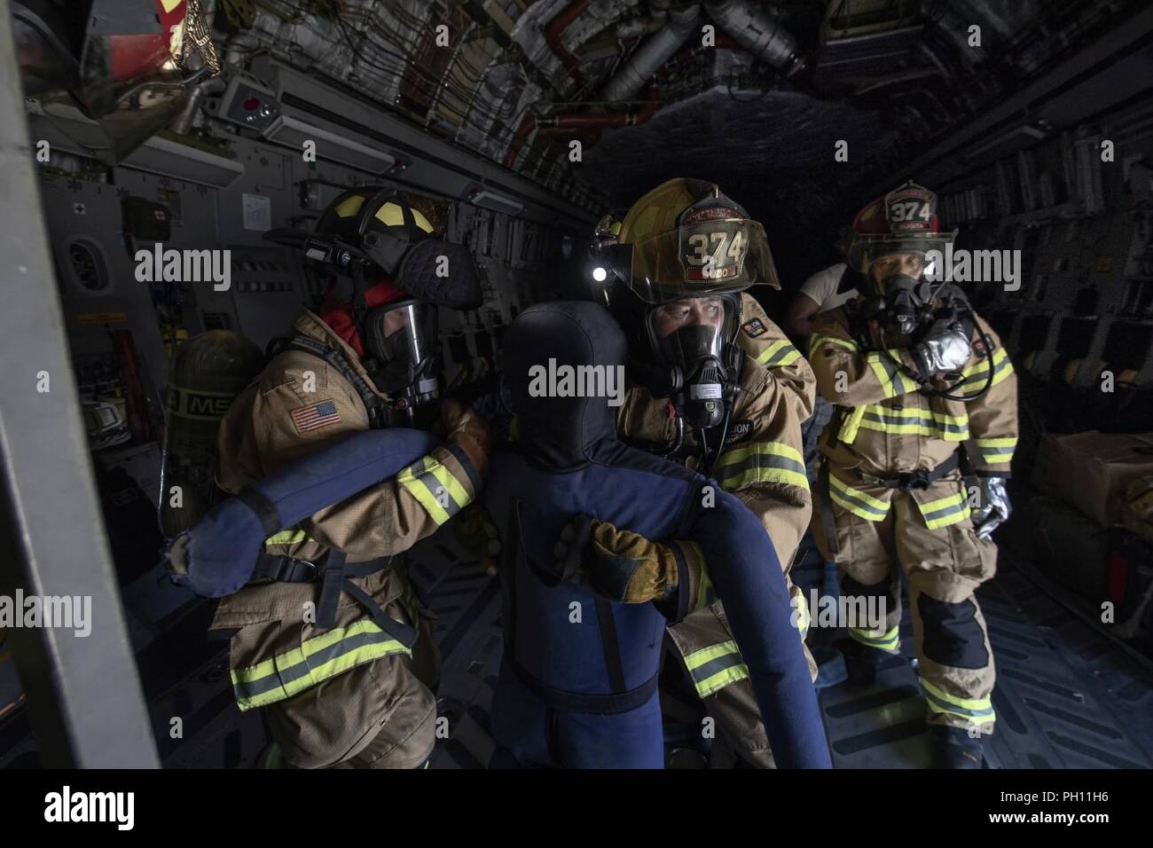Feuerwehrmänner vom 374 Bauingenieur Squadron einen simulierten Patienten aus einer C-17 Globemaster III Cockpit während ein Notfallplan Übung in Yokota Air Base, Japan, 25. Juni 2018 ziehen. Flieger von der 730th Air Mobility Squadron und 374 CES Feuerwehr führte eine simulierte Feuer an Bord einer C-17 und Einarbeitung Training. Stockfoto