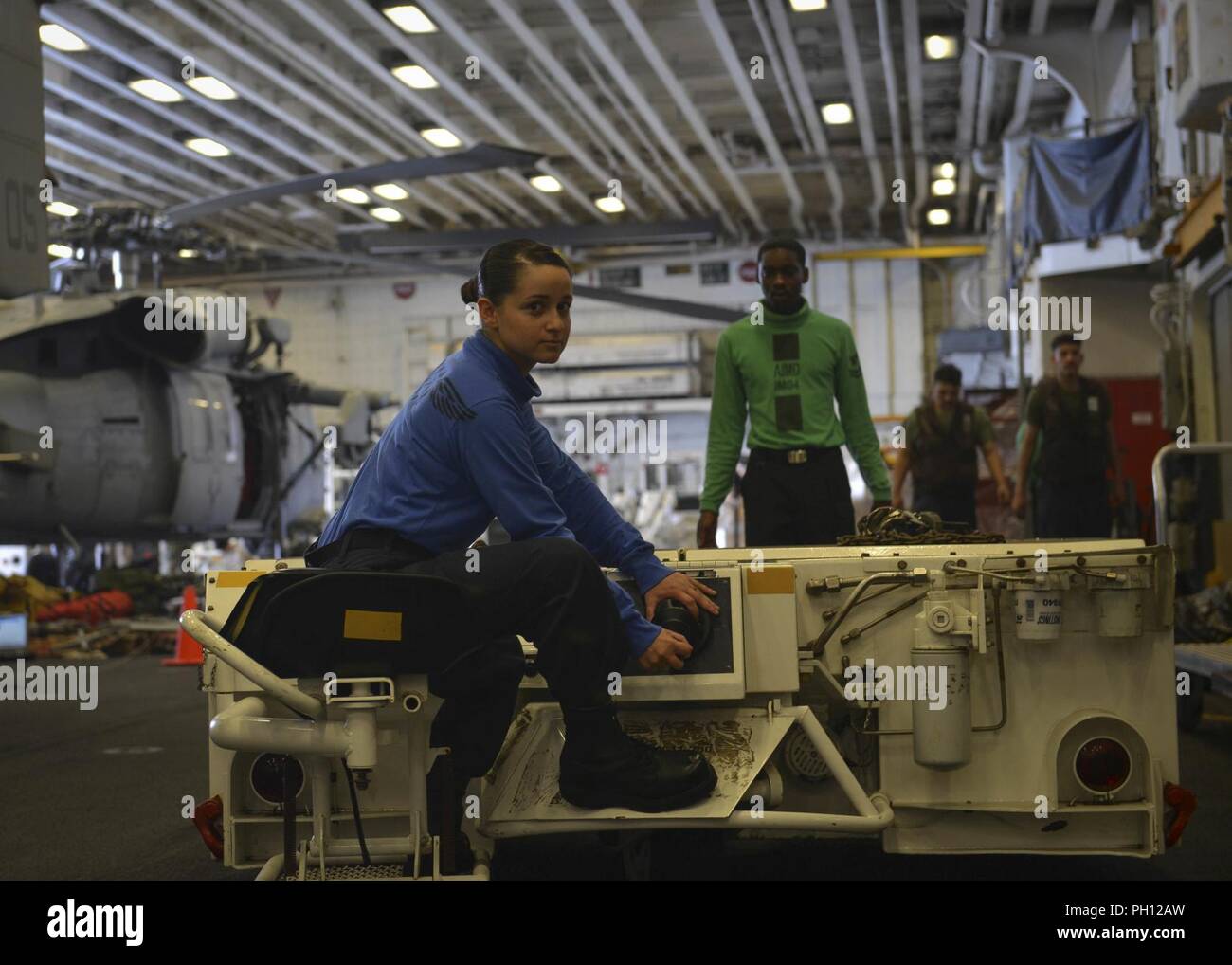 5. Flotte BEREICH VON OPERATIONEN (26. Juni 2018) der Luftfahrt Bootsmann Mate (Handling) 3. Klasse Alejandra Lozada, Paso Robles, Kalifornien, treibt einen wie 32-32 ein Spotting dolly im Hangar Bucht von der WASP-Klasse amphibisches Schiff USS Iwo Jima (LHD7), 26. Juni 2018. Iwo Jima in Mayport, Fla. homeported, ist auf die Bereitstellung zu den USA 5 Flotte Bereich für Maßnahmen zur Erhöhung der Sicherheit des Seeverkehrs Operationen Verbündeten und Partnern zu beruhigen, und der Freiheit der Schiffahrt und des freien Handels in der Region erhalten. Stockfoto