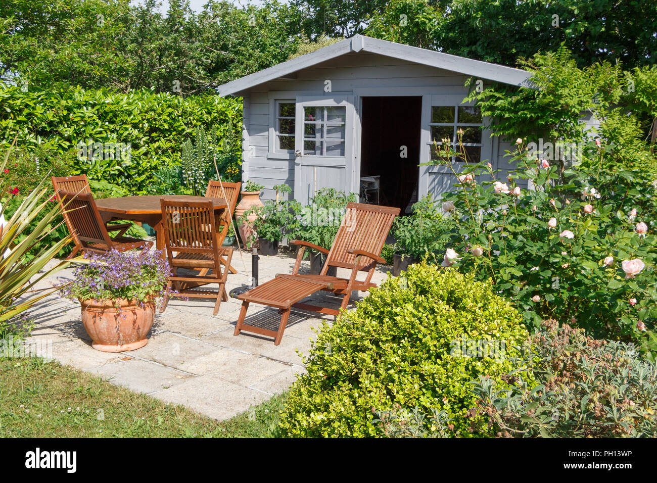 Graue Schuppen mit Terrasse und Gartenmöbeln aus Holz Stockfoto