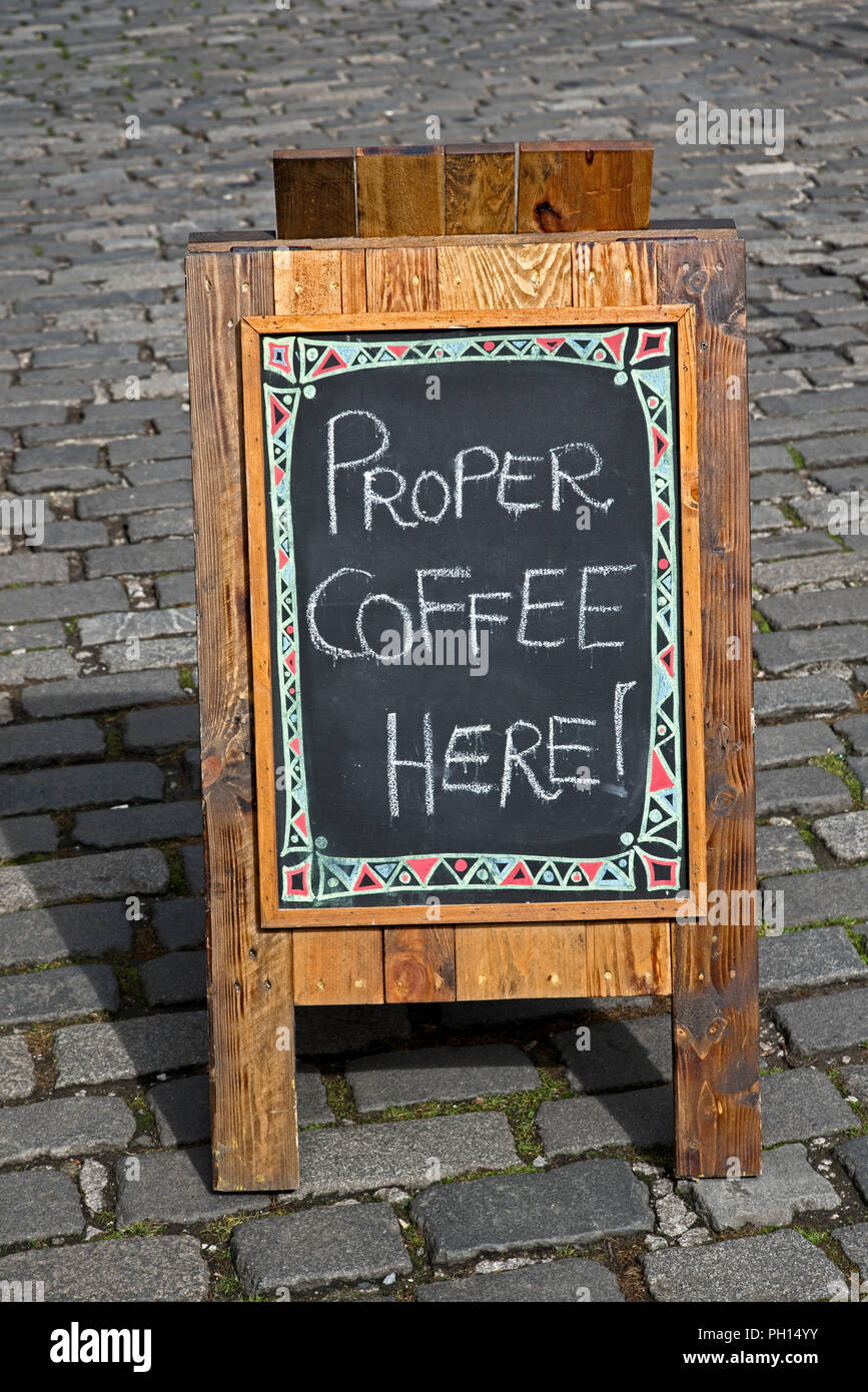 Ein A-Brett auf einer gepflasterten Straße Werbung "richtigen Kaffee". Stockfoto