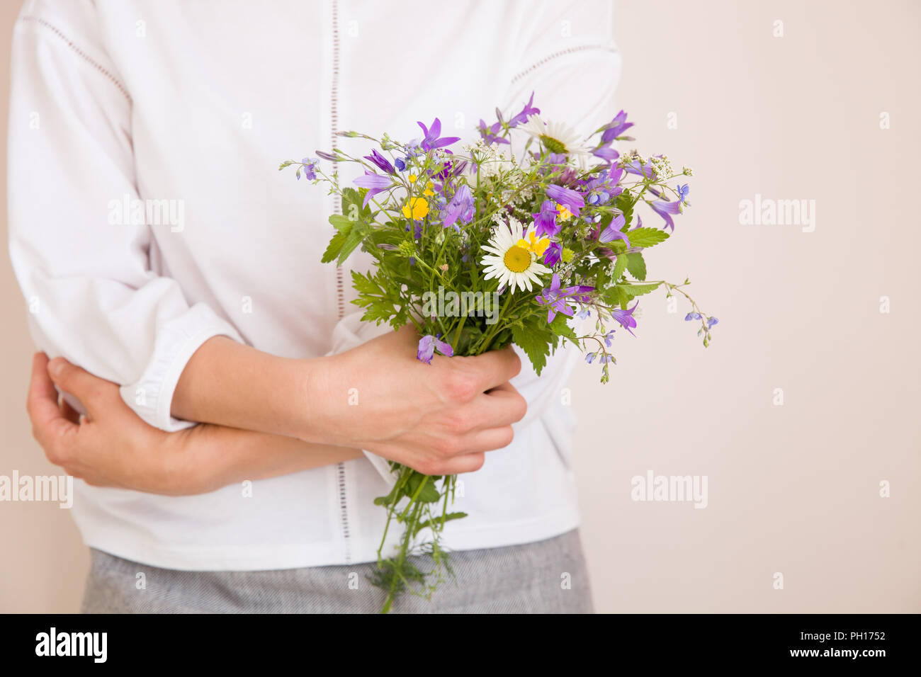 Nahaufnahme der Frau Hände halten schöne Bündel von wilden Blumen. Mädchen mit Sommer bouquet weiße Wand. Stockfoto