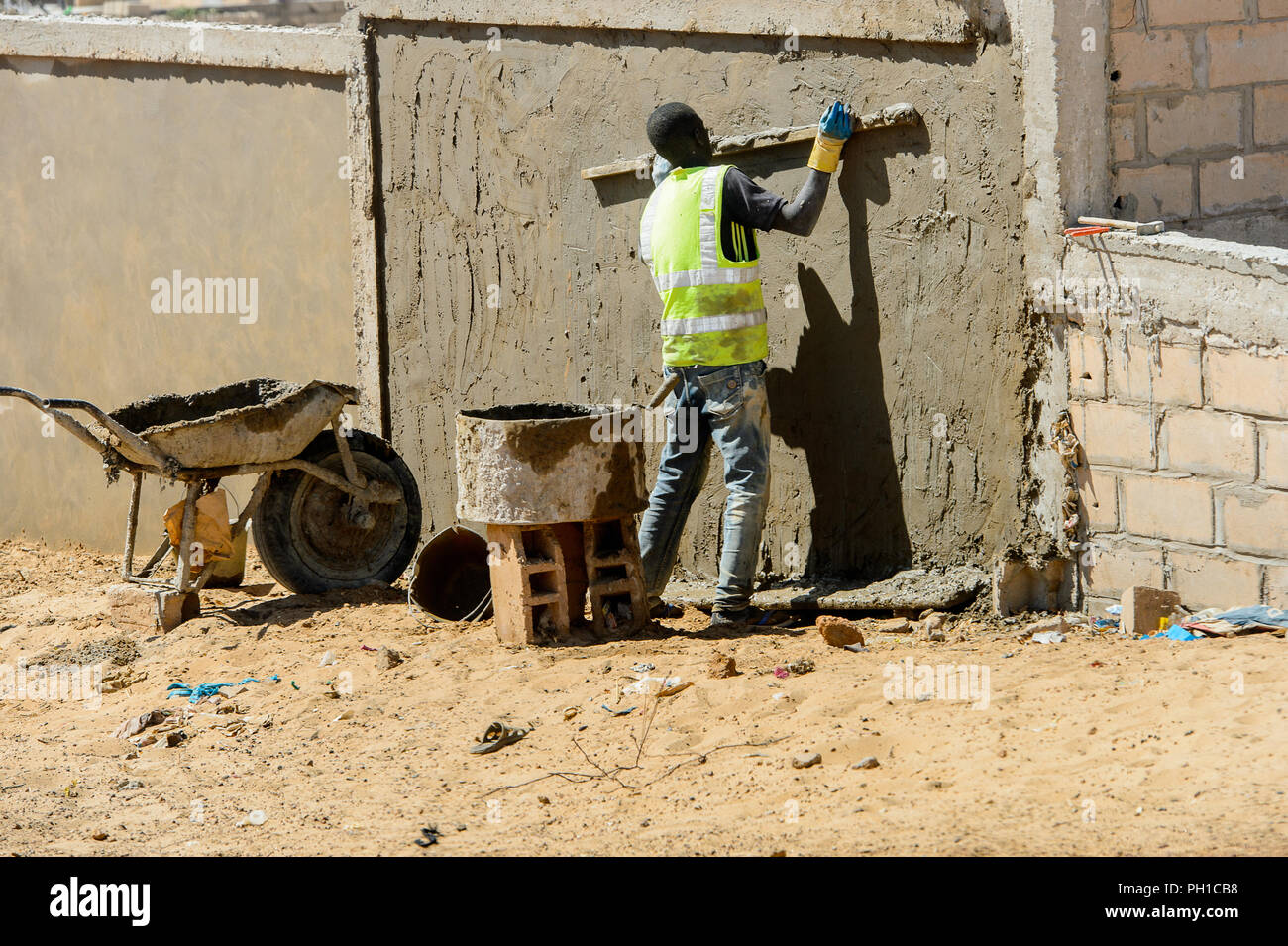 Weg zum Kalvarienberg, SENEGAL - 23.April 2017: Unbekannter senegalesischen Mann flacht die Wand mit Hilfe von hölzernen Stock. Noch viele Menschen im Senegal l Stockfoto