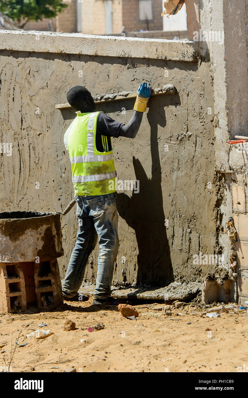 Weg zum Kalvarienberg, SENEGAL - 23.April 2017: Unbekannter senegalesischen Mann flacht die Wand mit Hilfe von hölzernen Stock. Noch viele Menschen im Senegal l Stockfoto