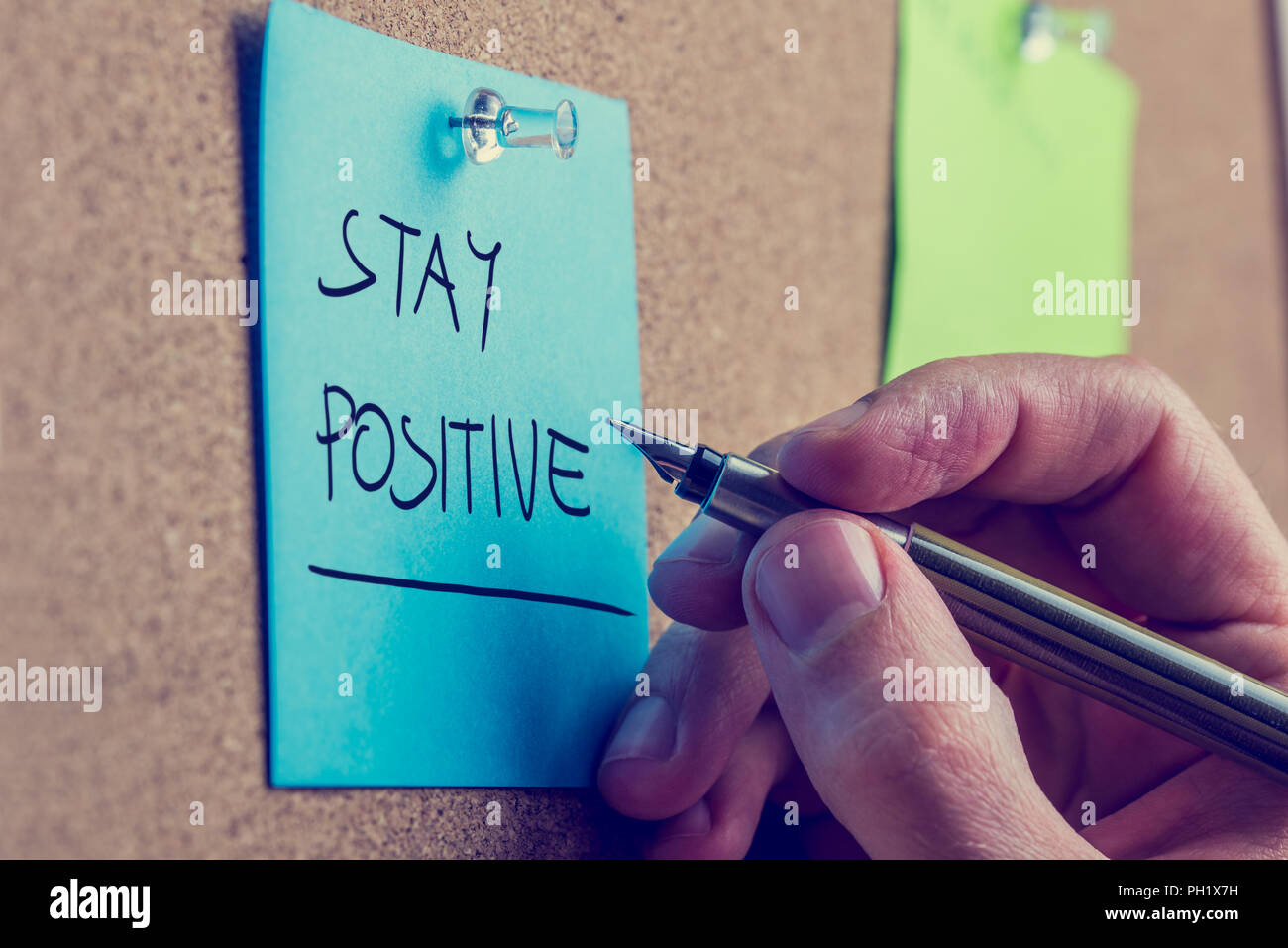 Retro instagram Stil Bild einer männlichen Hand schreiben Aufenthalt auf blauer Post it Papier auf Kork Pinnwand angeheftet positiv. Stockfoto