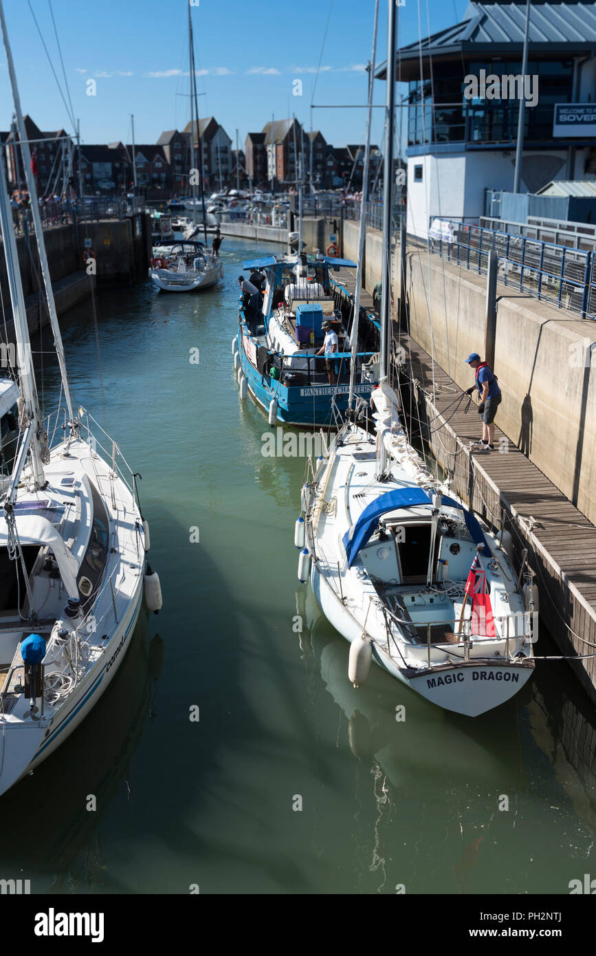 Kleine Boote eingabe Sovereign Harbour über die Schleusentore in Eastbourne, East Sussex, England, UK. Stockfoto