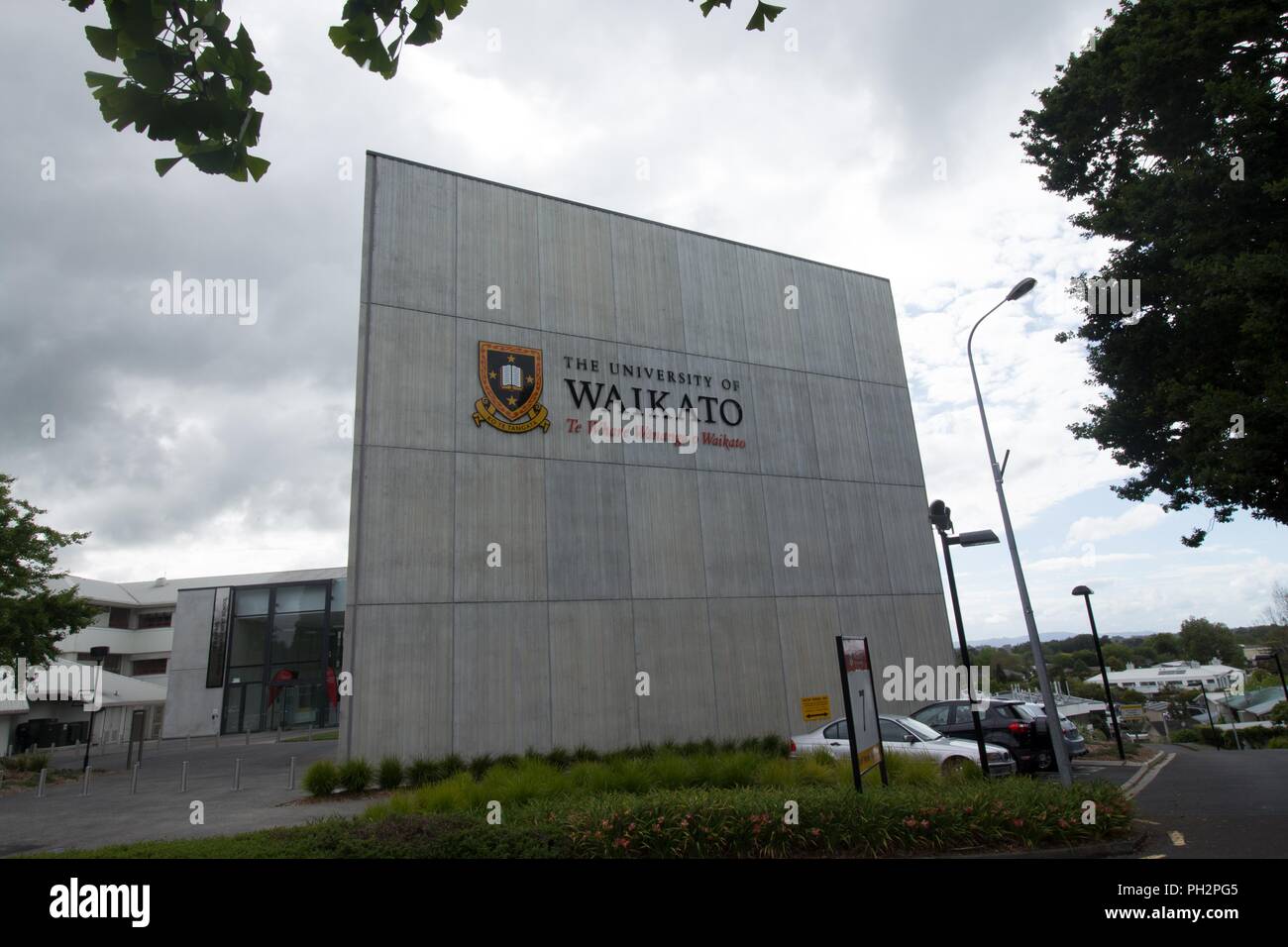 Schild mit Campus Gebäude im Hintergrund an der Universität Waikato in Hamilton, Neuseeland an einem bewölkten Tag, November, 2017. () Stockfoto