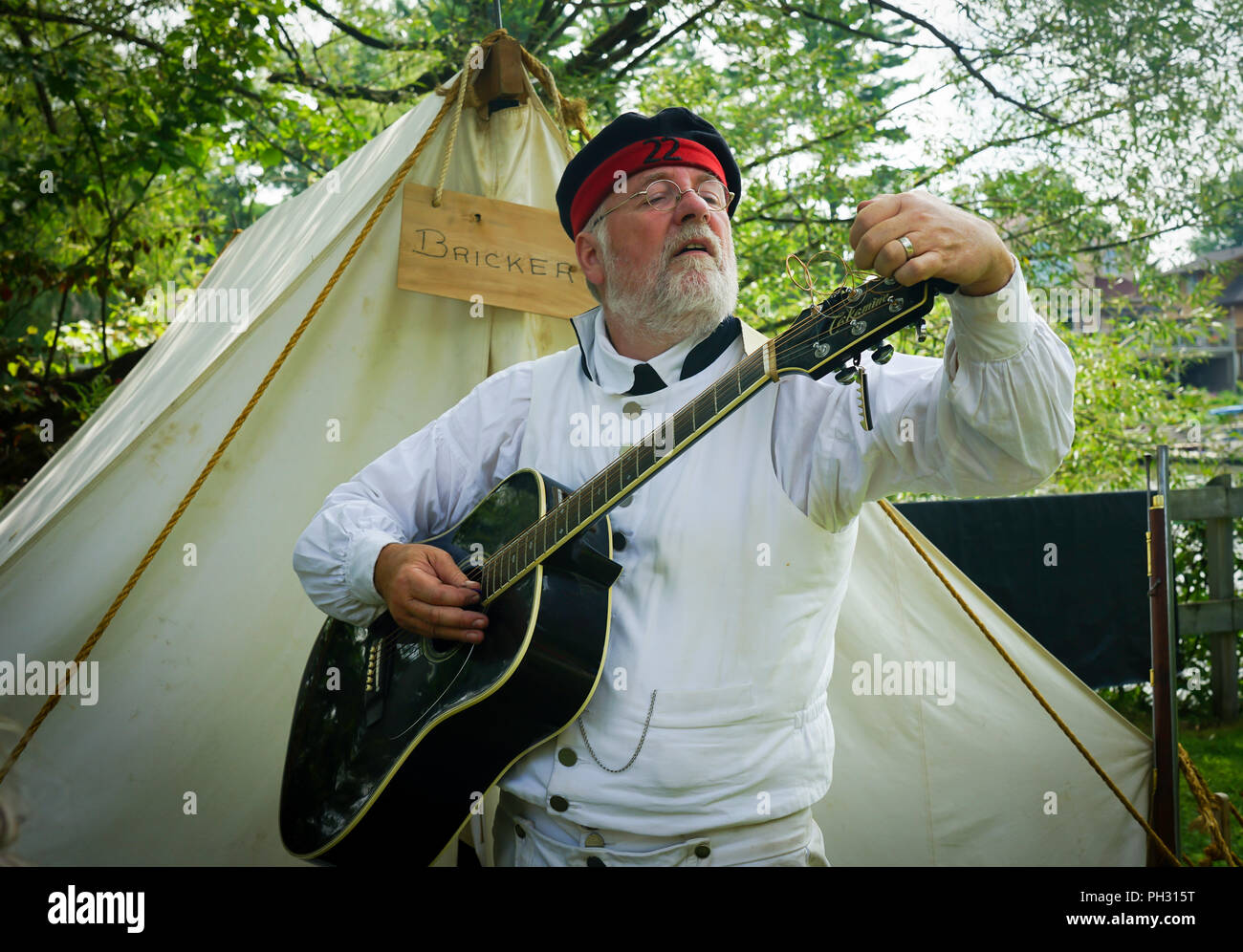 Soldat tuning seine Gitarre britischen Militärs, Royal Navy, US-amerikanischen militärischen Encampment mit Reenactors mit Piraten, Voyageurs und Royal Nanvy Gun Crew. Stockfoto