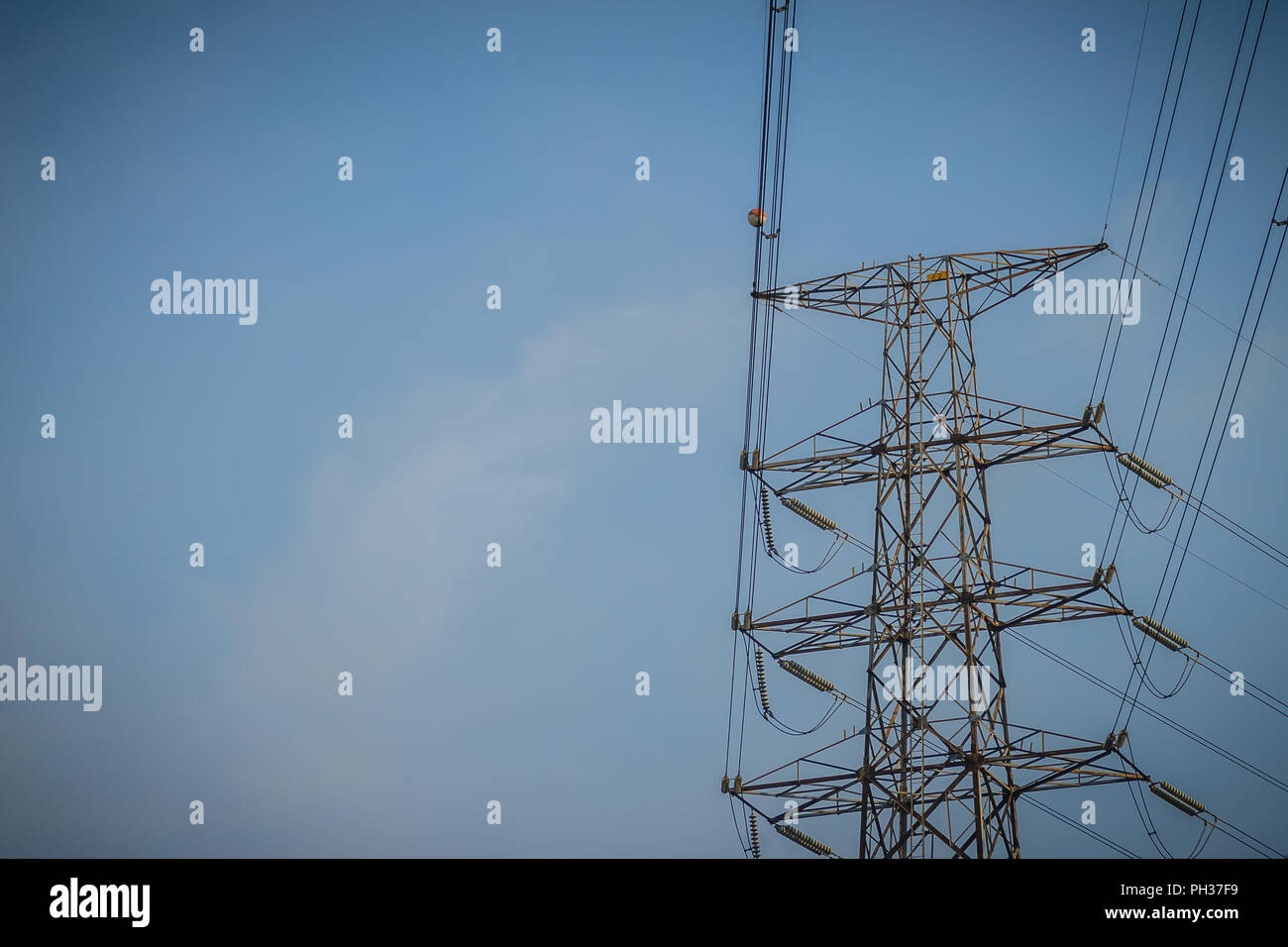 Angesichts der hohen Spannung post am blauen Himmel Hintergrund. Elektrische übertragung Turm mit Kabel in Himmel Hintergrund. Stockfoto
