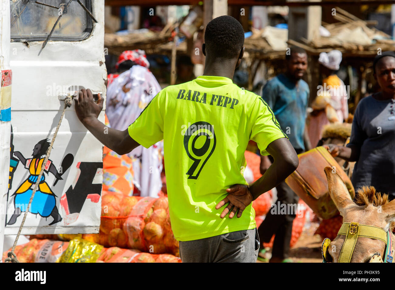 KAYAR, SENEGAL - Apr 27, 2017: Unbekannter senegalesischen Mann in Grün shirt lehnt sich an die Tür des Auto auf dem lokalen Markt von Kayar, Senegal. Stockfoto
