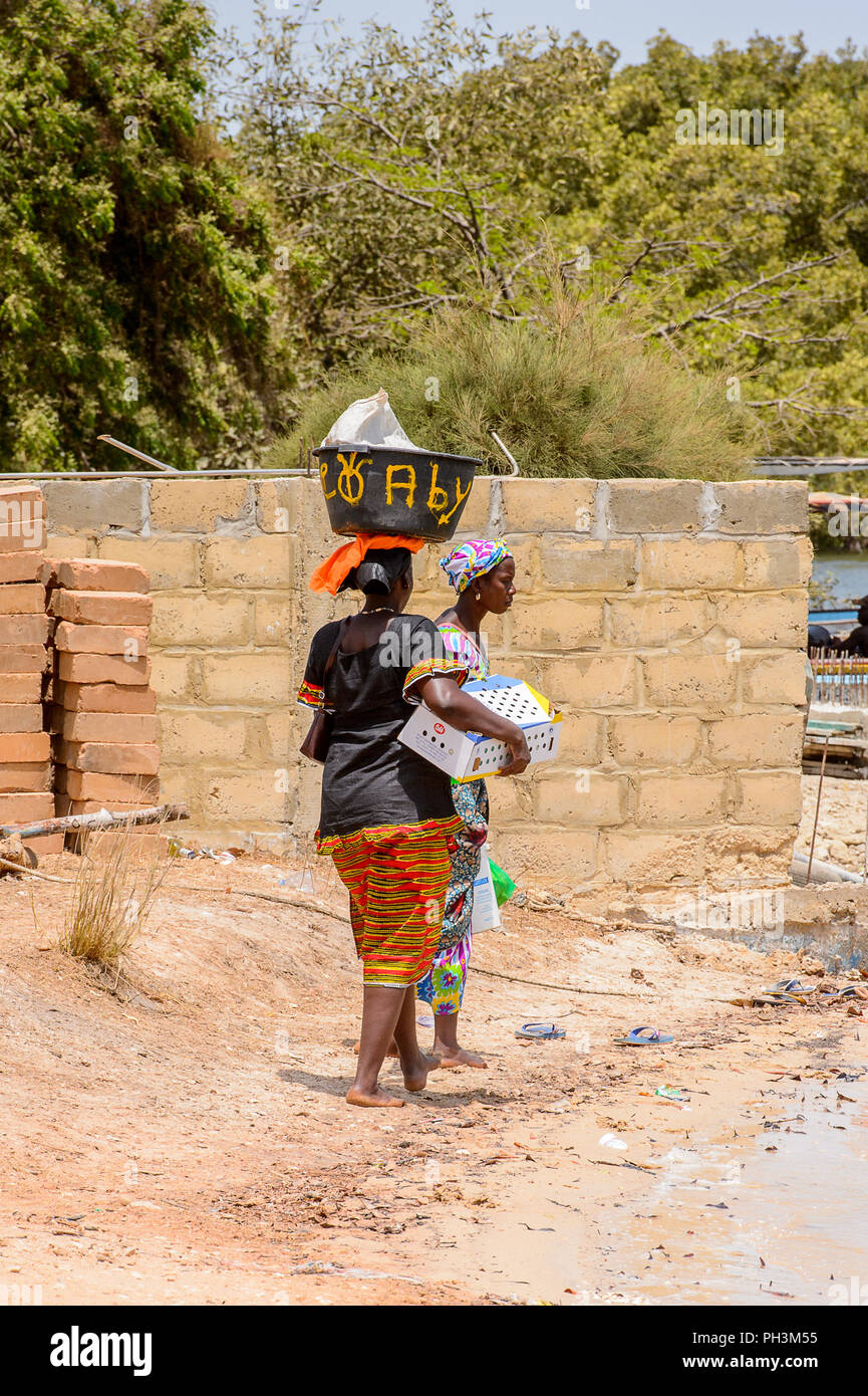 CASAMANCE FLUSS, SENEGAL - APR 29: Unbekannter senegalesische Frau trägt ein Becken auf dem Kopf am Strand entlang an der Küste der Casamance Fluss Stockfoto