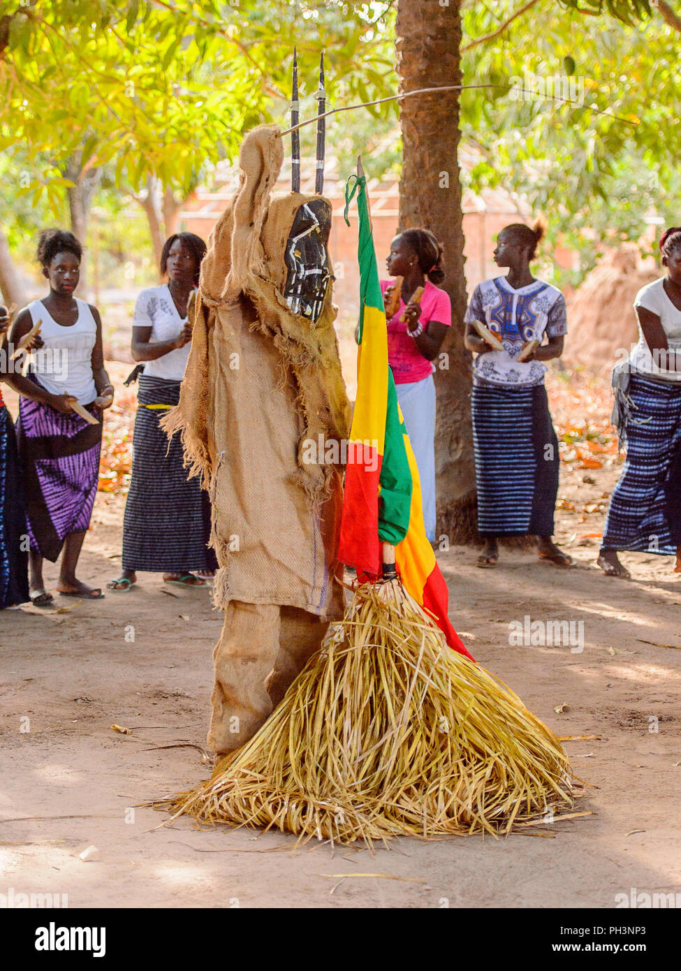 Kaguit vil., SENEGAL - Apr 30, 2017: Unbekannter Diola Mann in einem Kostüm steht in der Nähe der Nationalen fllag während ein traditioneller Tanz Kumpo in einem Heiligen F Stockfoto