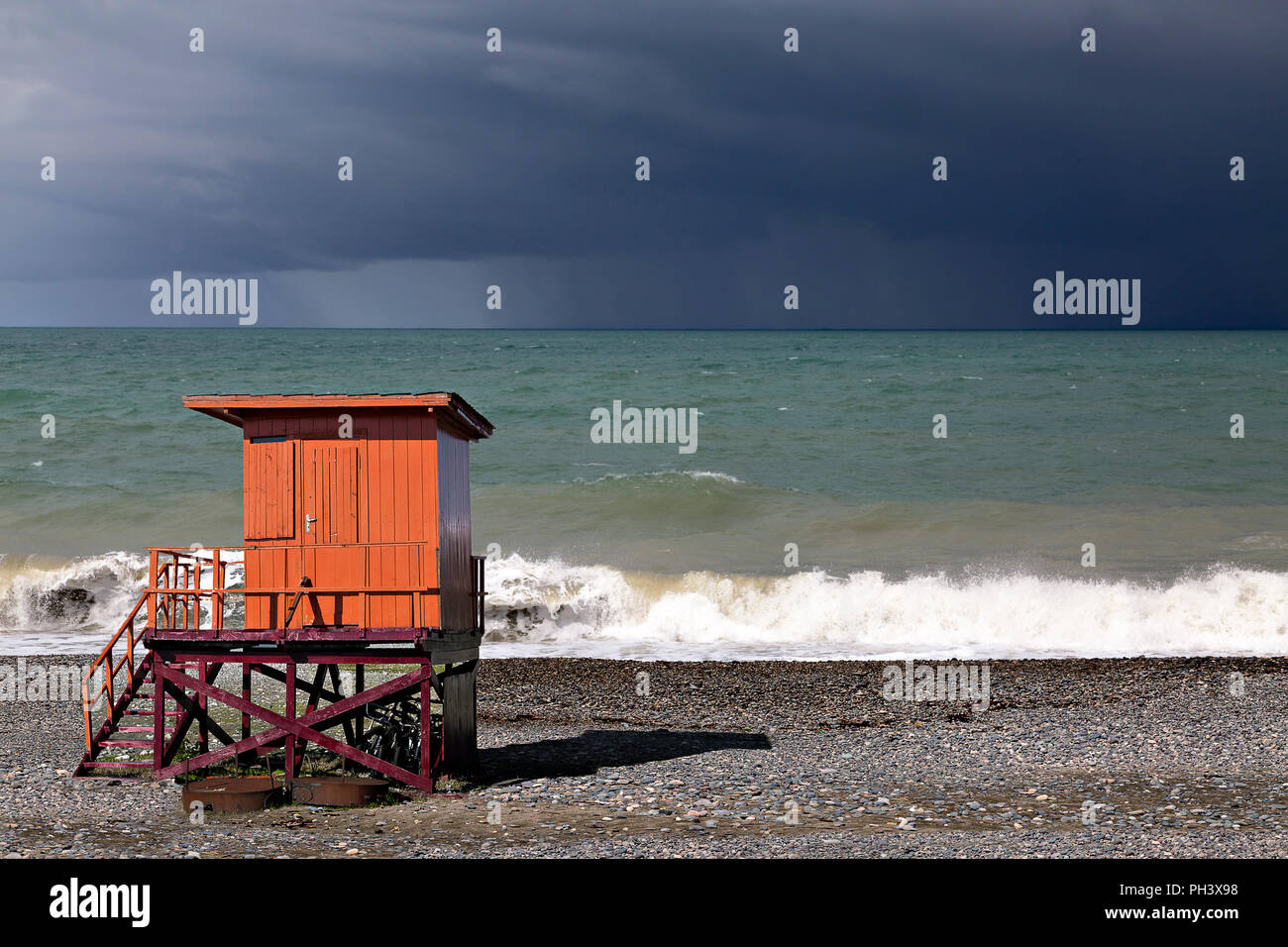 Orange Rettungsschwimmer Hütte am Schwarzen Meer mit dunklem Himmel im Hintergrund, in Batumi, Georgien. Stockfoto
