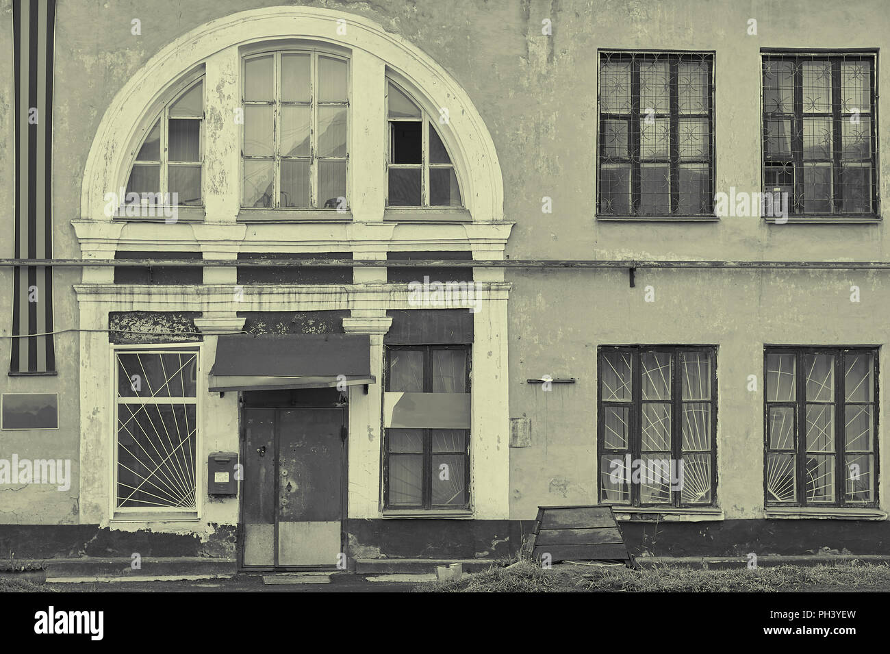Alten, verlassenen Fabrik Fassade mit einem großen Fenster und rostiges Metall Tür in Schwarz und Weiß Stockfoto