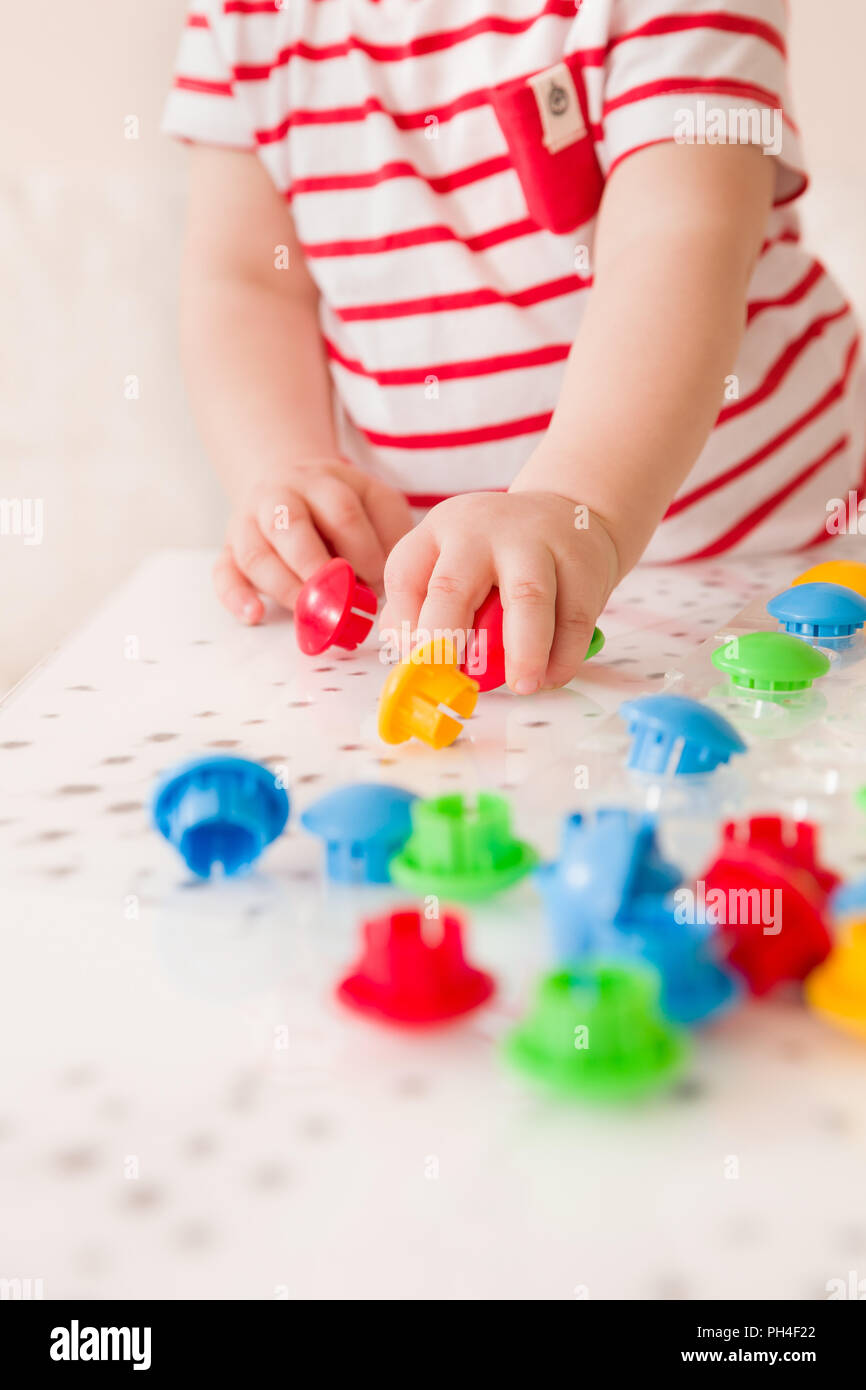 Nahaufnahme der Hand des Kindes, die hellen Mosaik Teile. Spielen und Lernen Farben zu Hause. Kleinkind Junge im gestreiften Hemd spielen mit bunten construc Stockfoto