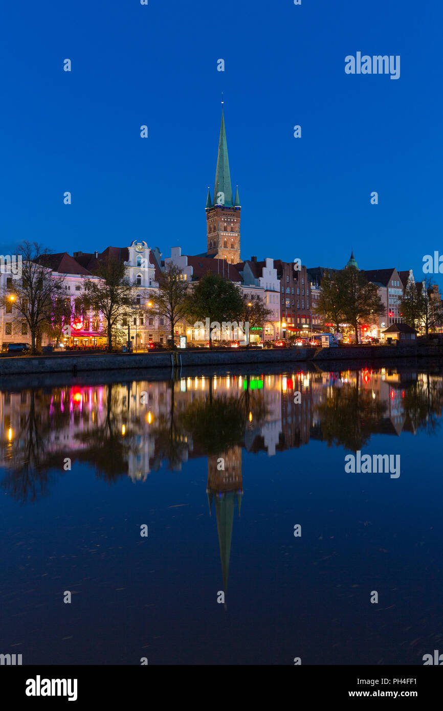 Die Kirche von St. Petri und historische Häuser spiegeln die Trave in Lübeck in der Abenddämmerung. Schleswig-Holstein, Deutschland. Stockfoto