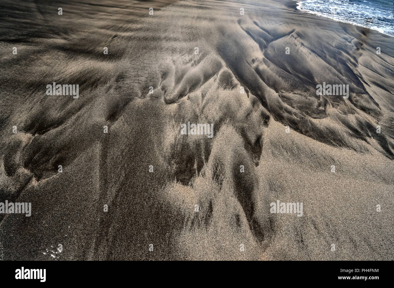 Wasser und schöne Muster von Wellen des Atlantik auf echten nassen schwarzen vulkanischen Sandstrand auf der Insel Madeira, Portugal. Texturierte backgroun Stockfoto