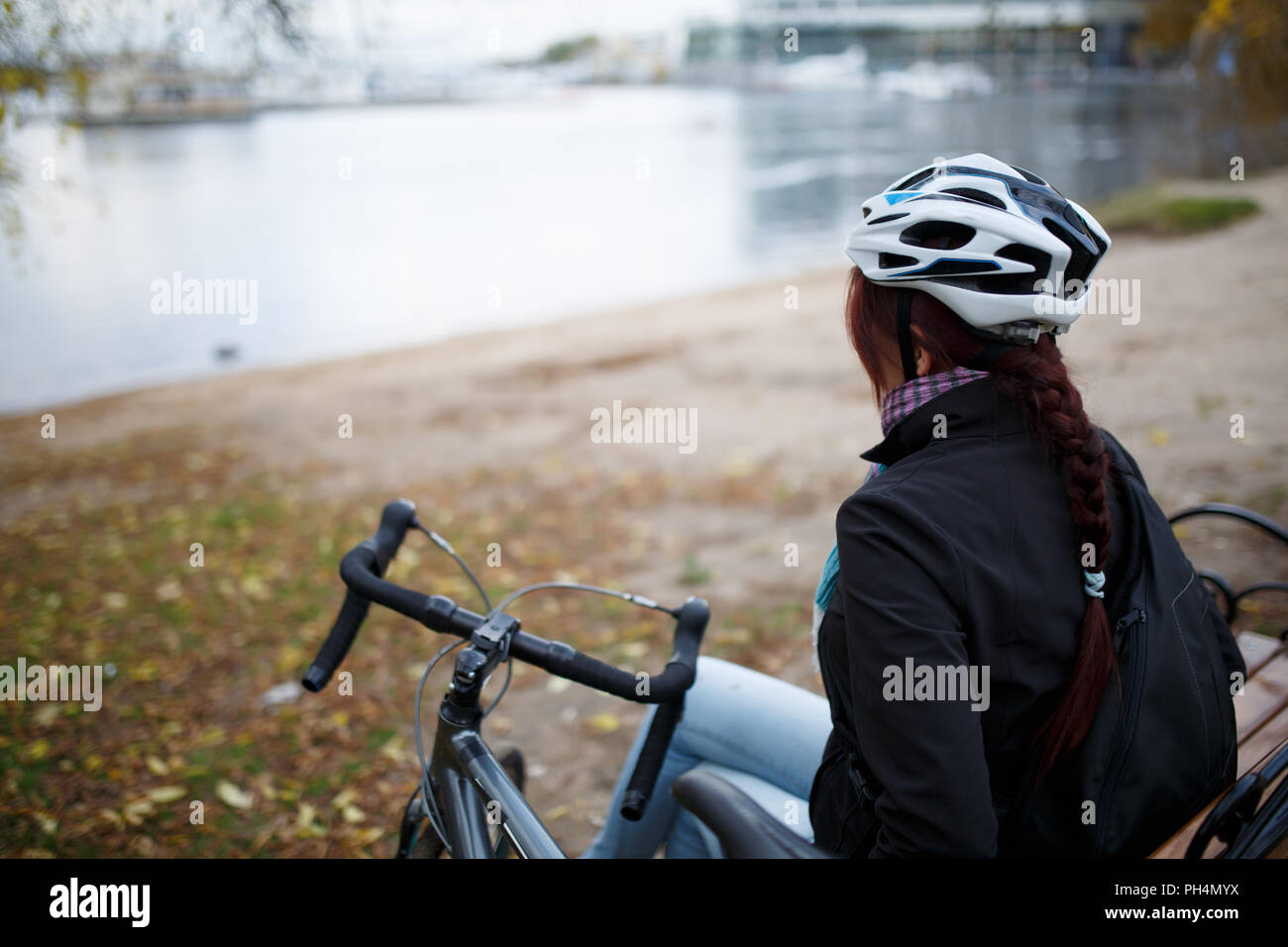 Foto von der Rückseite der Mädchen im Helm neben Fahrrad auf Teich Stockfoto