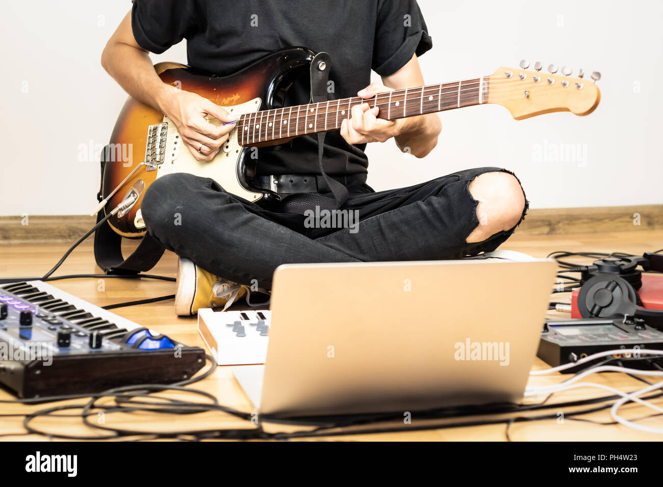 Männliche Gitarrist spielt E-Gitarre an modernen Home Studio- und Proberaum. Junger Mann, Produktion von Musik mit elektronischen Effekten Prozessoren, synthesi Stockfoto