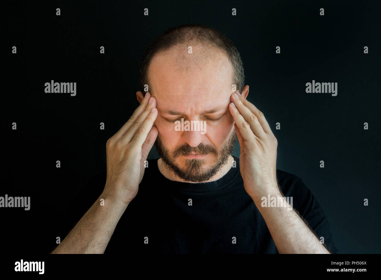 Ernster Mann mit Bart und Schnurrbart auf schwarzem Hintergrund in Low Key, Frustration und Verzweiflung Geste Stockfoto