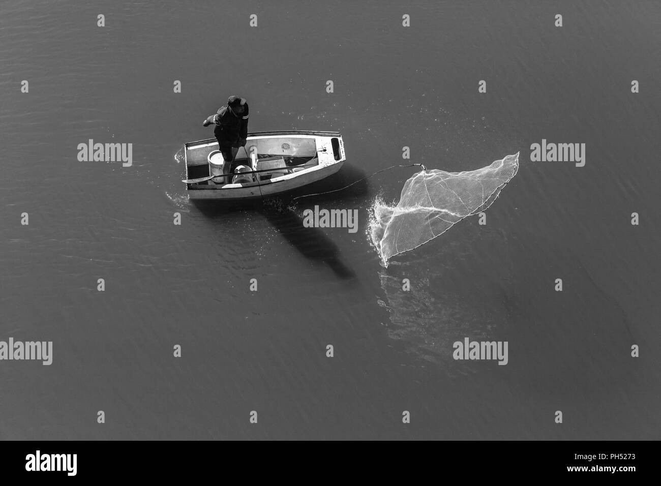 Fischer casting net Aktion, um die Fischerei mit kleinen Boot in Fluss Wasser der Lagune overhead Foto Stockfoto