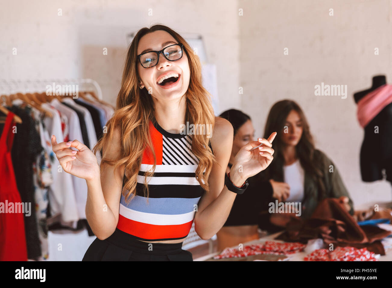 Glückliche junge Frau Kleidung Designer im Atelier Studio arbeiten mit  Kollegen auf Hintergrund Stockfotografie - Alamy