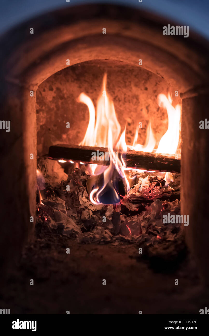 Brennendes Feuer in einem Steinofen, Nahaufnahme, Low Key Stockfoto