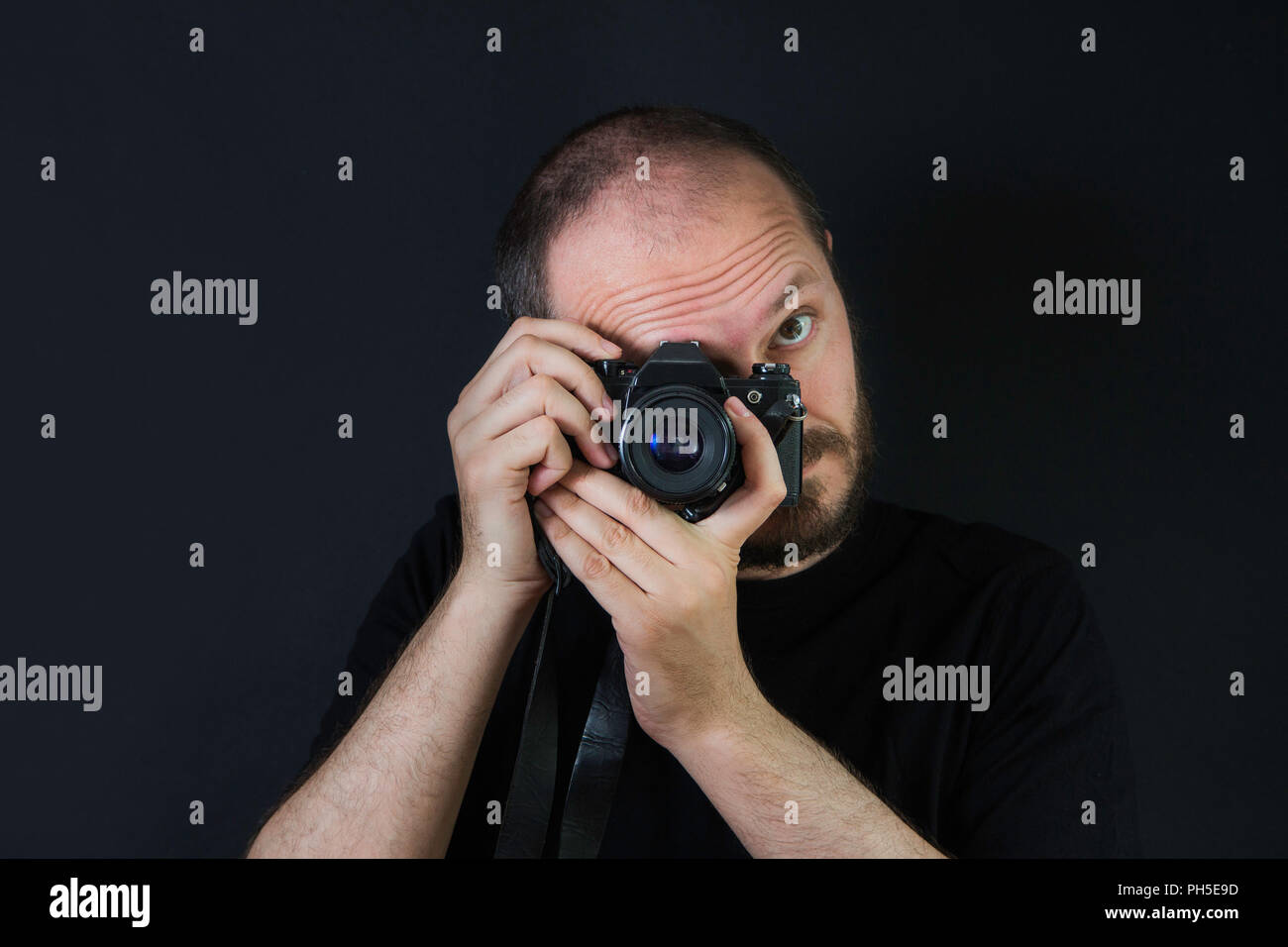Mann auf schwarzem Hintergrund in Low Key, analoge Kamera und Aufnehmen von Fotos Stockfoto