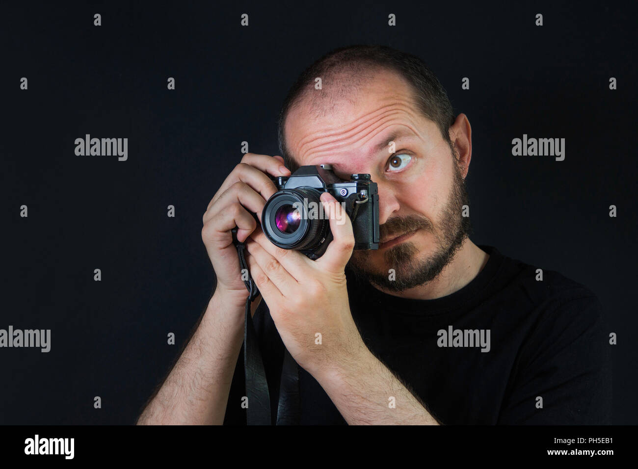 Mann auf schwarzem Hintergrund in Low Key, analoge Kamera und Aufnehmen von Fotos Stockfoto
