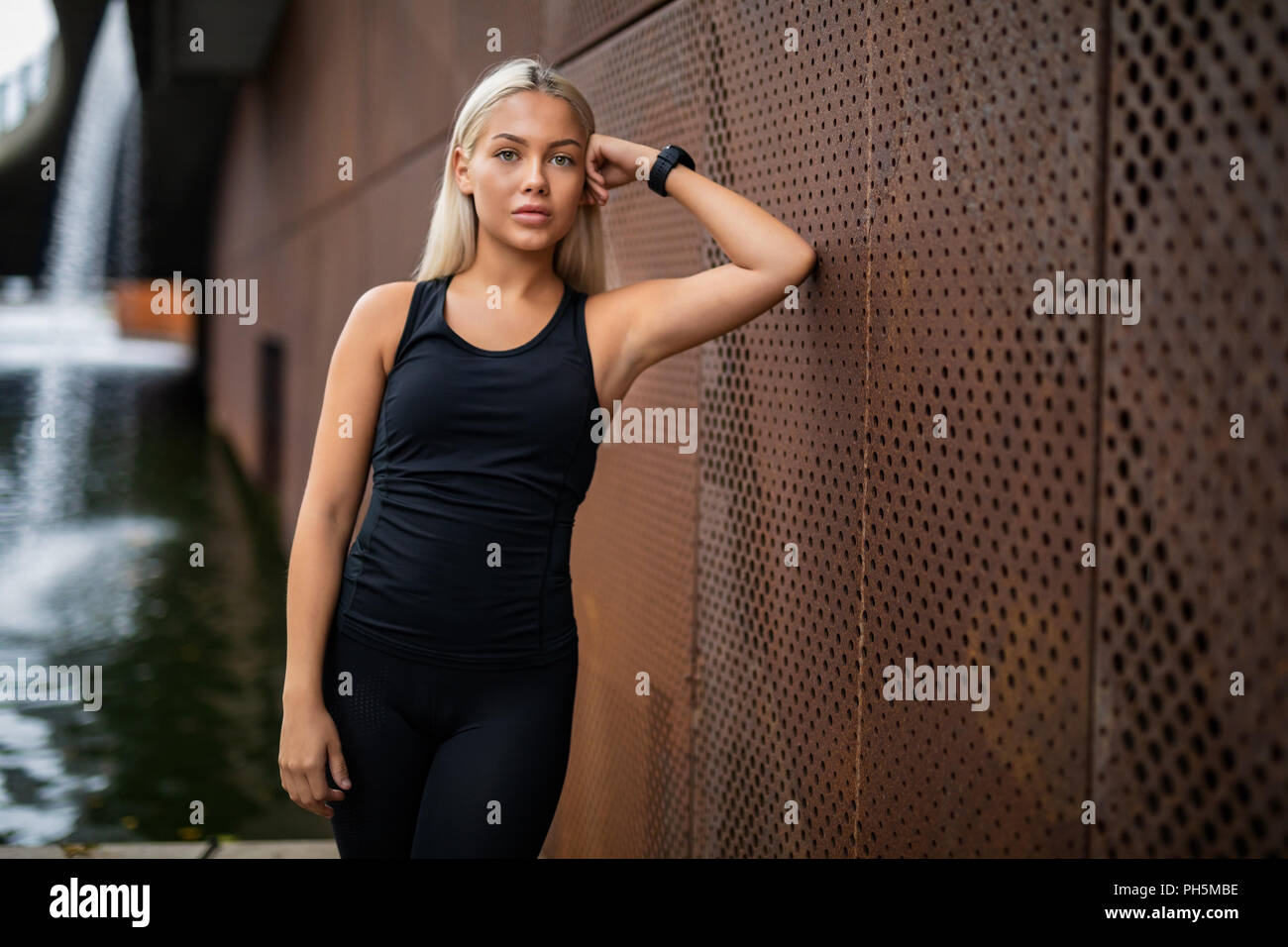 Passen junge Frau lehnte sich auf metallische Wand nach dem Workout Stockfoto