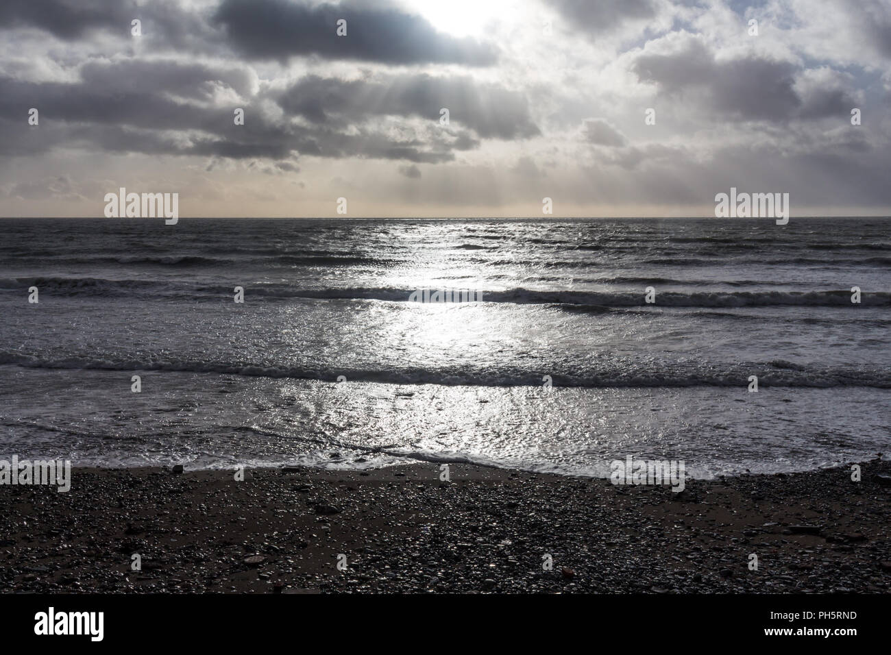 Sonnenlicht, das durch die Wolken über dem Meer gegen einen felsigen Ufer plätschern, St. Johns Point, County Down, Nordirland. Stockfoto