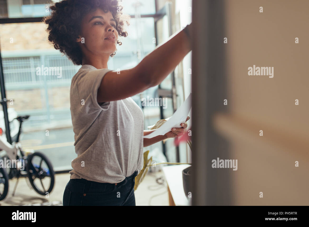 Geschäftsfrau Schreiben auf dem Whiteboard an. Junge afrikanische Frauen arbeiten bei tech Start schreiben Neues Projekt Plan an Bord. Stockfoto
