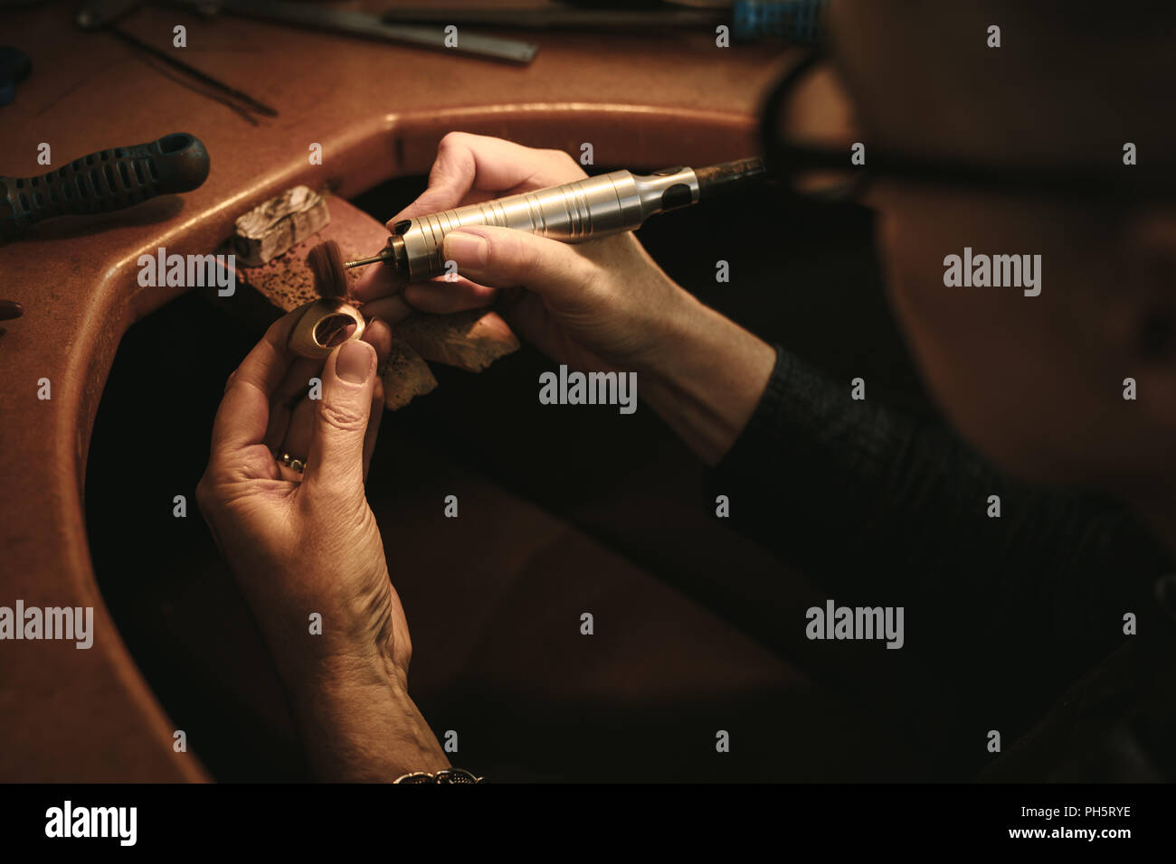 Die Hände der älteren Frau Goldsmith polieren Sie die scharfen Kanten auf einem Ring an ihrer Werkbank. Schmuck Designer machen ring Oberfläche nahtlos, mit Polieren Stockfoto