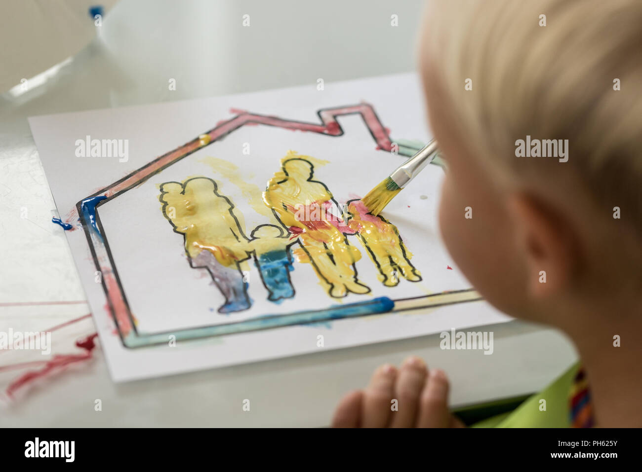 Junge Spaß malen ein Bild in eine Familie in einem Haus mit bunten Wasser Color Farben in einem über die Schulter sehen. Stockfoto