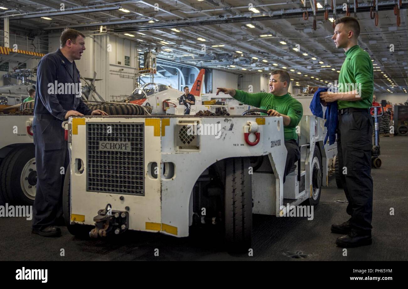 Atlantischer Ozean (25. Juni 2018) Aviation Support Equipment Techniker 3. Klasse Donald Vannah, von Litchfield, Maine, zeigt in die Richtung, in die er die Verlegung wird eine spotting Flaschentransportwagen für Hubschrauber an Bord der Flugzeugträger USS George H.W. verwendet Bush (CVN 77). Das Schiff ist im Gange, die Durchführung von routinemäßigen Übungen Träger bereit zu halten. Stockfoto