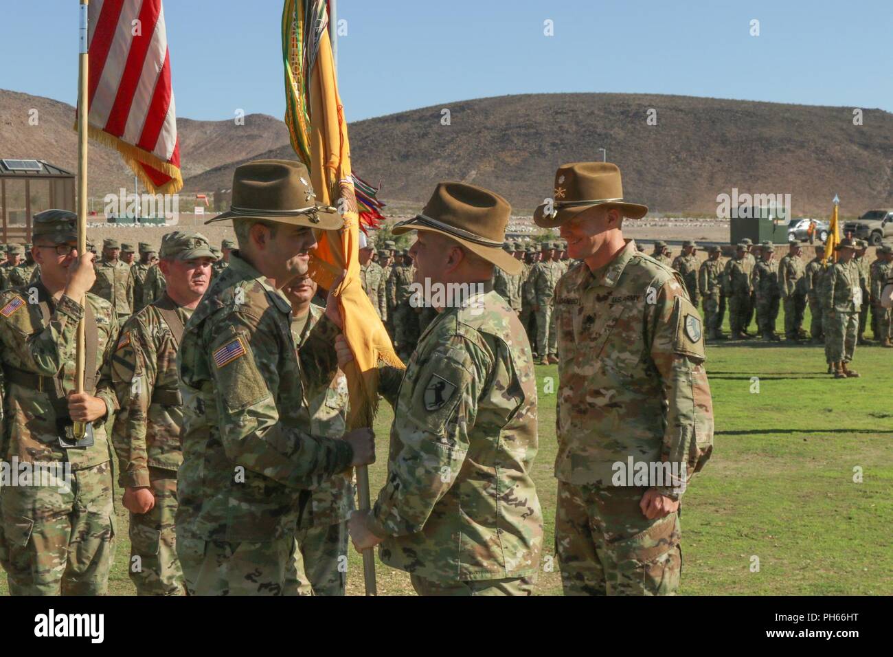 Us-Armee Oberst Joseph Clark, Commander, 11 gepanzerte Kavallerie Regiments, übergibt die 1. Staffel, 11. ACR Farben auf eingehende Kommandeur, Oberstleutnant Thomas Frohnhoefer, während der ironhorse Ändern des Befehls, auf Fort Irwin's Fritz Feld, 27. Juni 2018. Diese Zeremonie ist die Hingabe und selbstlosen Dienst nachgewiesen durch Oberstleutnant Danbeck zu gedenken und leitete ein neues Kapitel für die ironhorse Geschwader mit Oberstleutnant Frohnhoefer. Stockfoto