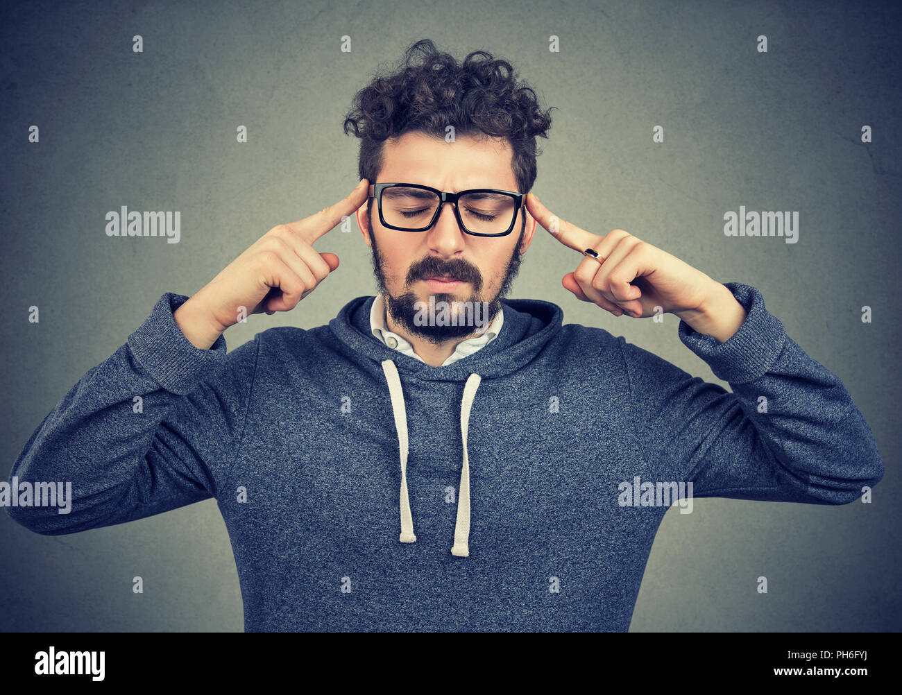 Erwachsenen Mann in Gläsern mit Fingern auf die Tempel, die versuchen, auf den Entscheidungsprozess konzentrieren. Stockfoto