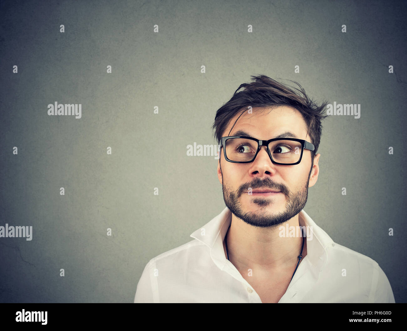 Gut aussehender bärtiger Mann, in der Kontemplation die Entscheidung auf grauem Hintergrund Stockfoto