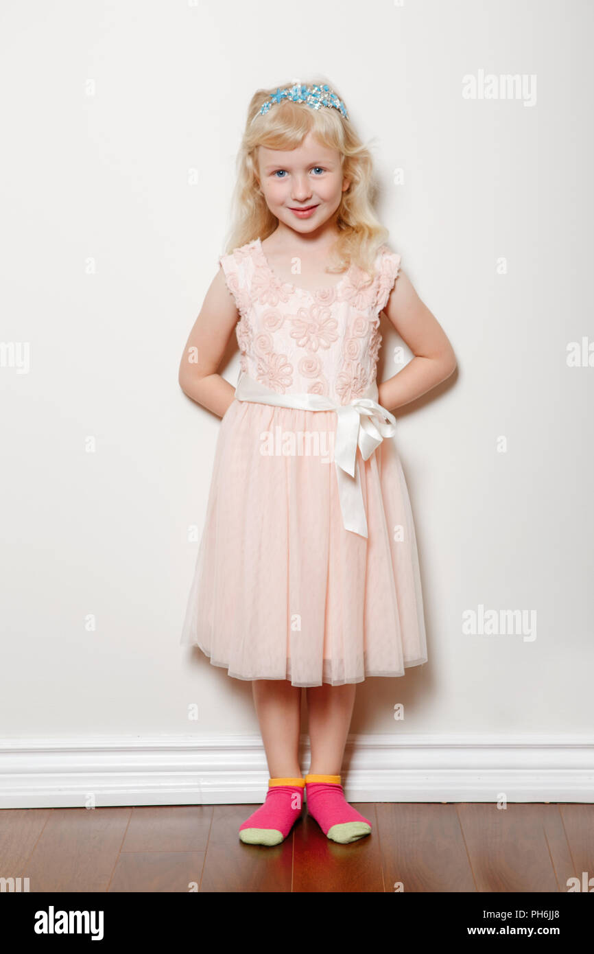 Full Body Home Portrait von cute adorable White blond fair Kaukasischen Vorschule Mädchen in rosa Kleid und Prinzessin Krone. Lächelnd Kind posiert im Innenbereich st Stockfoto