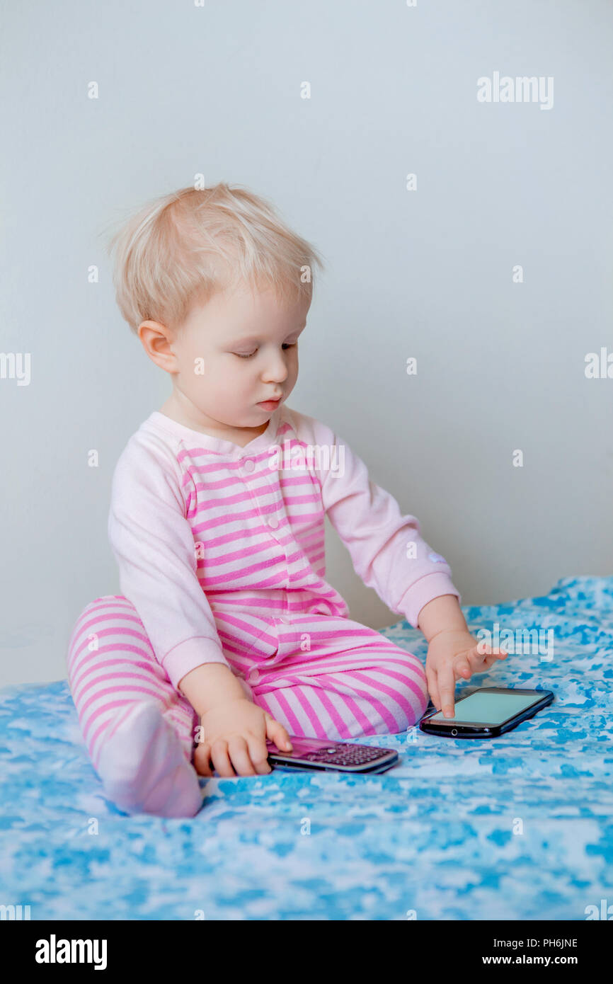 Cute adorable white Kaukasischen blond Baby einen Anruf machen, Spielen mit Handy mit lustigen Gesichtsausdruck, Lifestyle neue Generation Technol Stockfoto