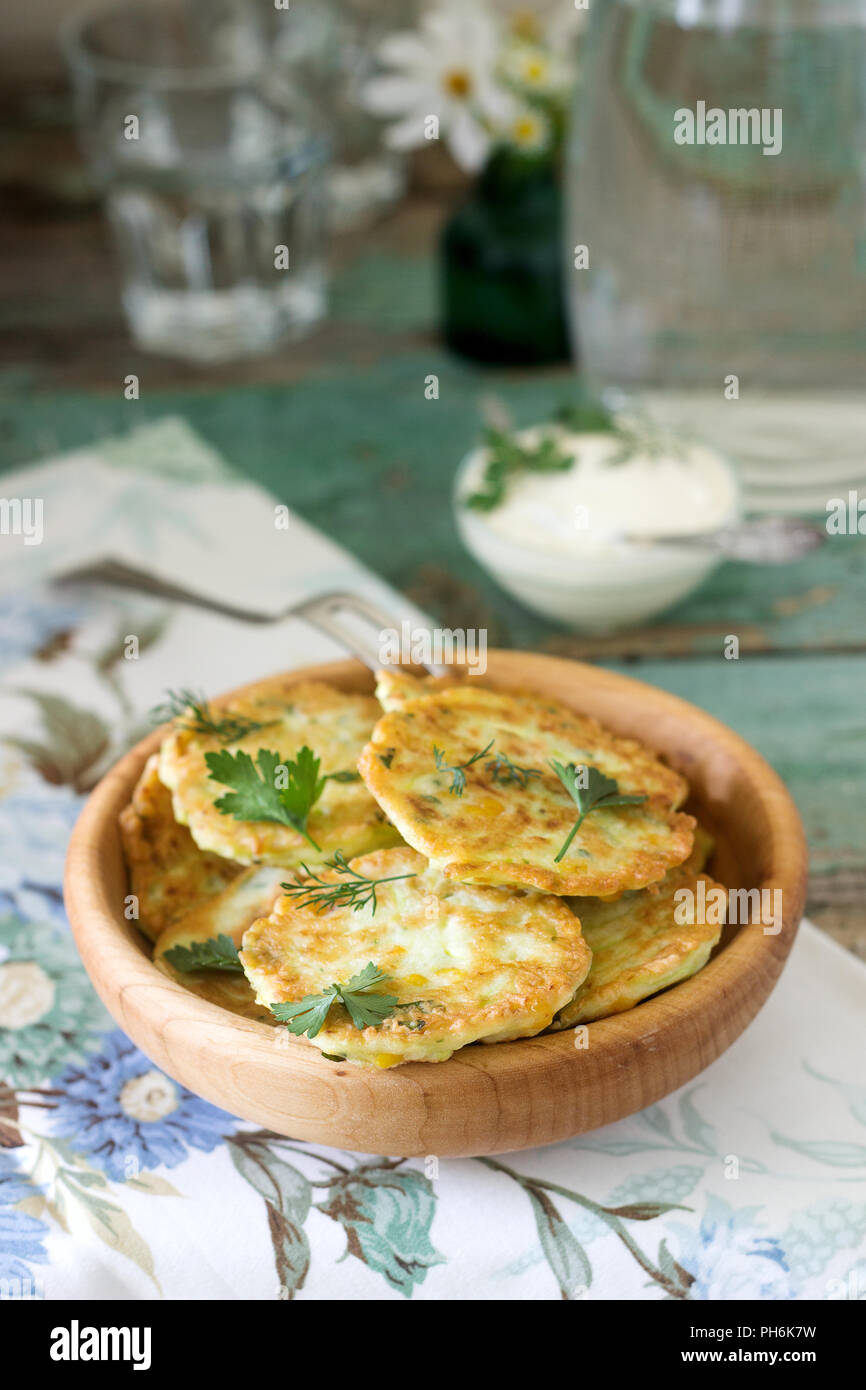 Pfannkuchen mit Zucchini und Mais, serviert mit saurer Sahne, Petersilie und Dill. Vegetarisches Essen. Stockfoto