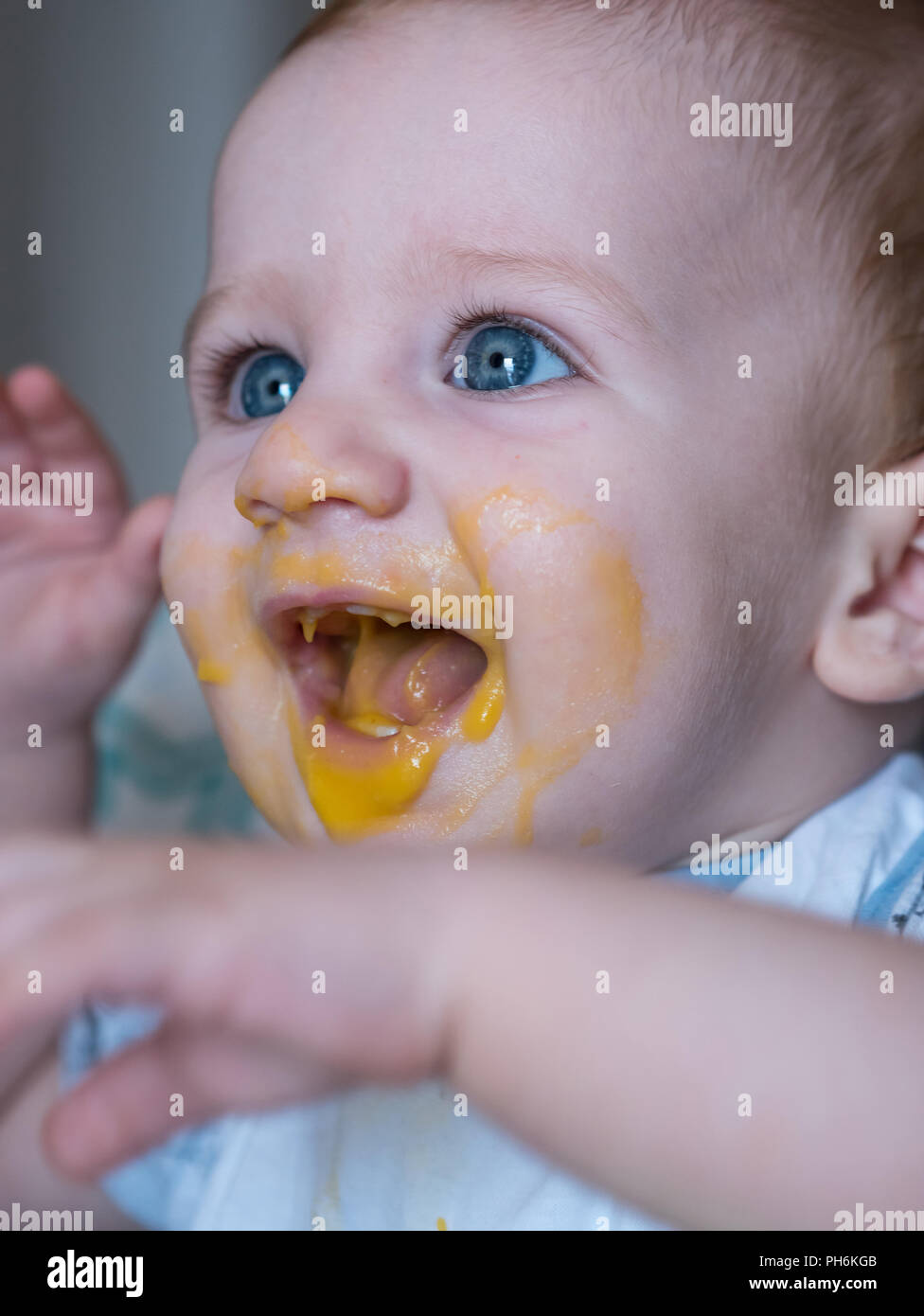 Unordentliche baby Junge mit blauen Augen zu Mittag gegessen und lächelnd Stockfoto