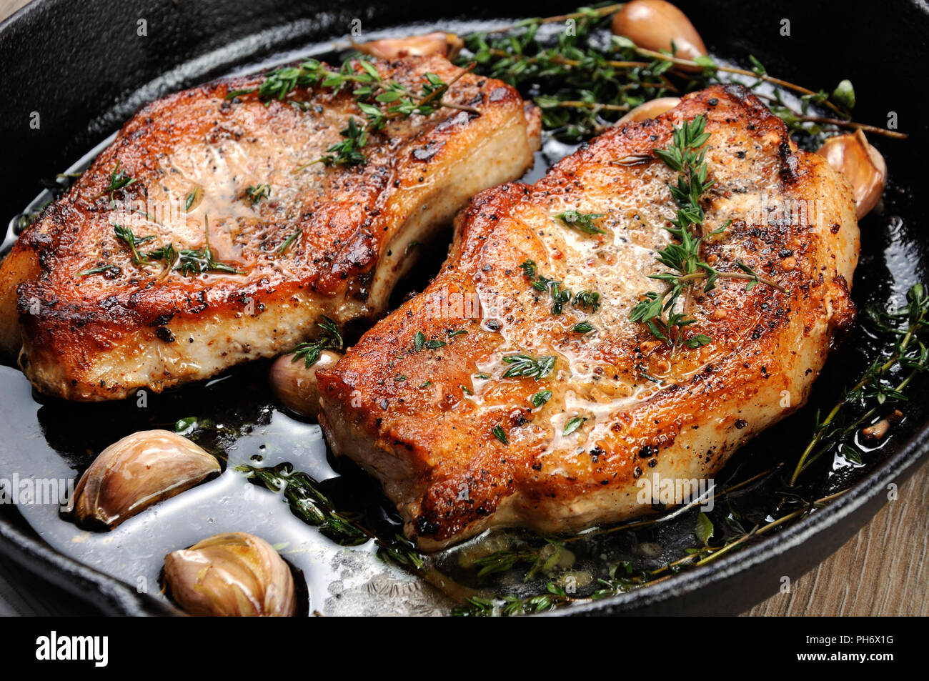 Saftig, brüniert Schweinesteak auf einen Knochen in Öl mit Knoblauch ...