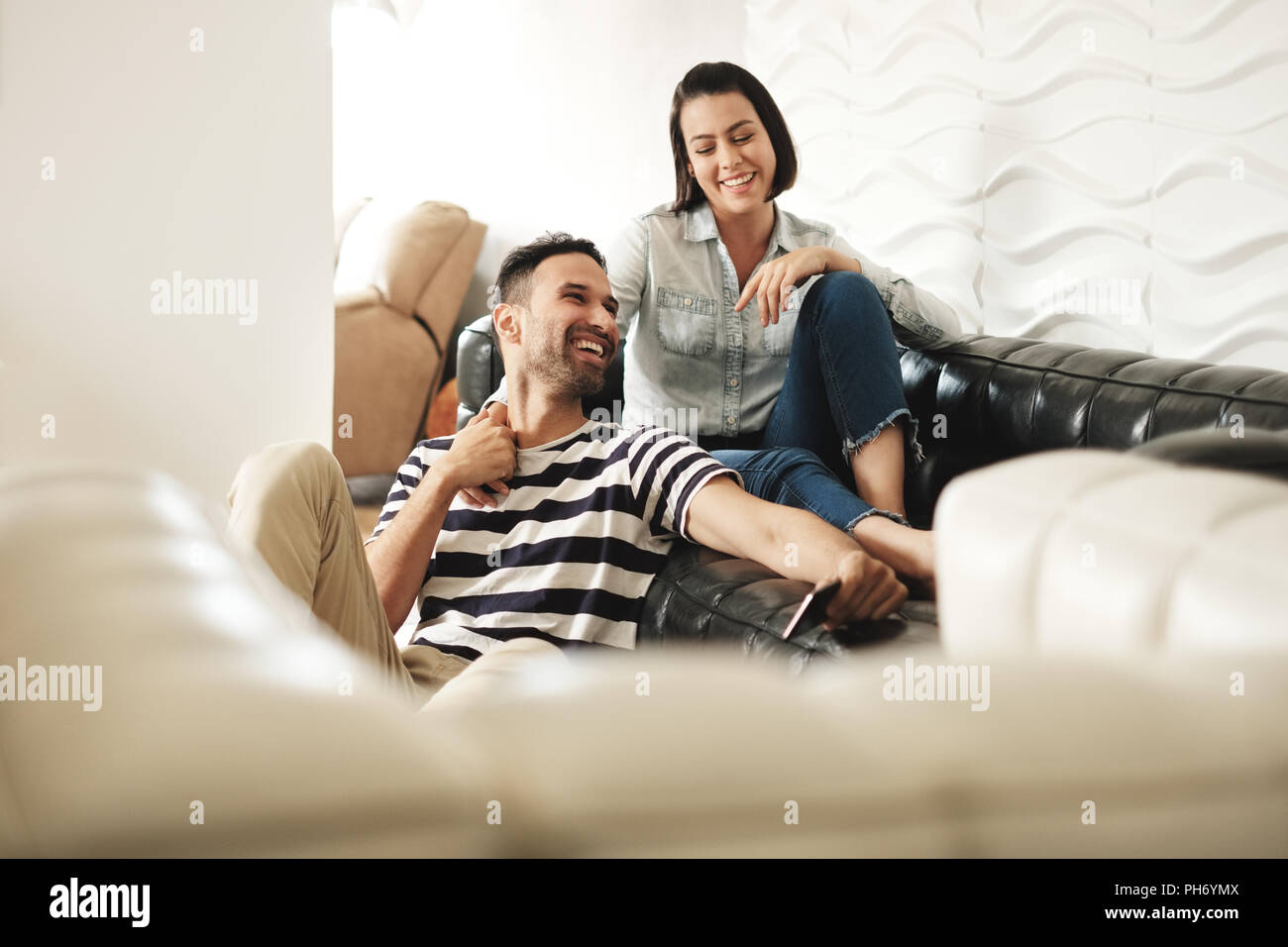 Happy Hispanic Paar mit Smartphones auf der Couch zu Hause Stockfoto