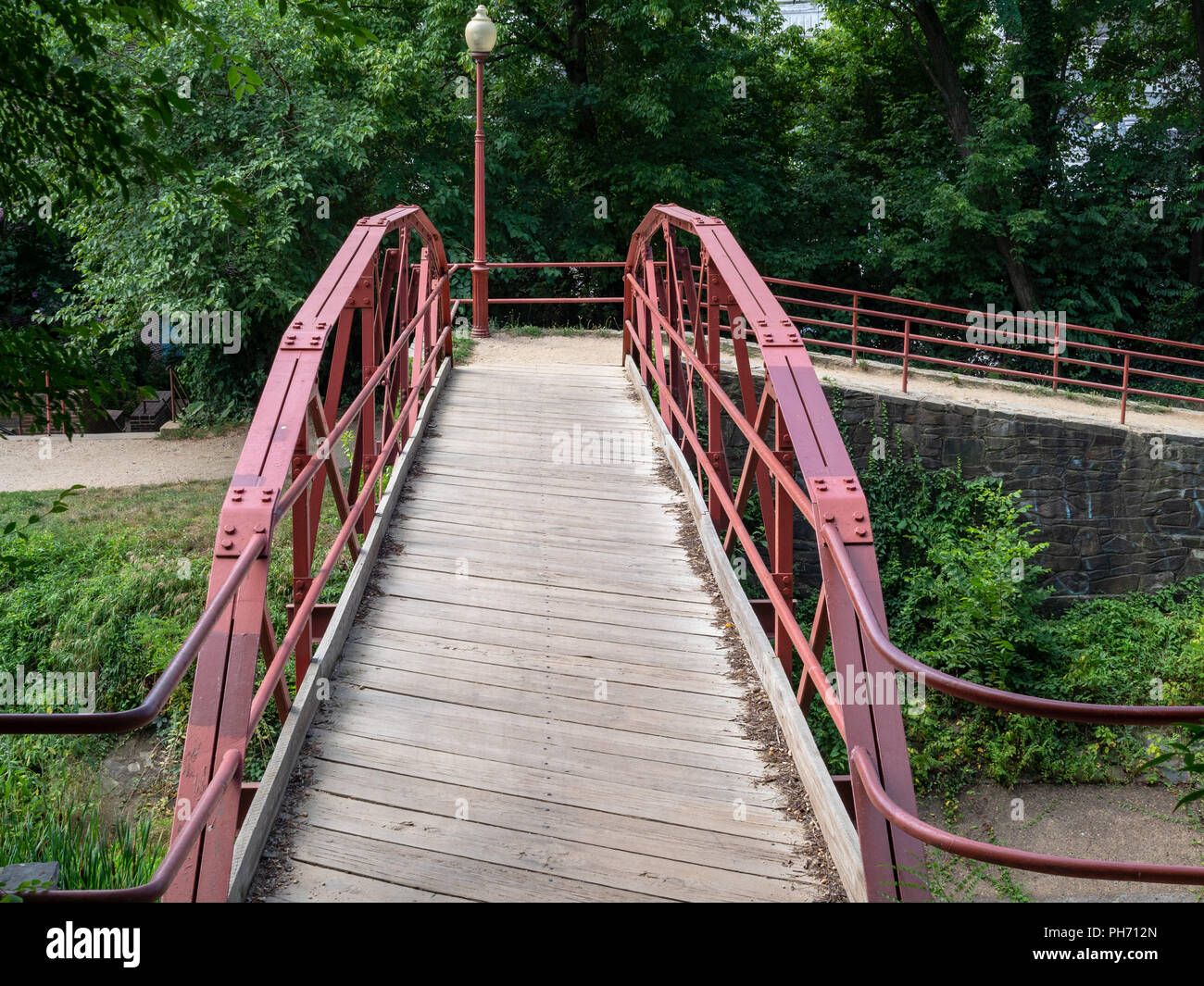Schmale Holzbrücke mit roter Stahl wachen führenden um Canal Gegend Fußweg Stockfoto