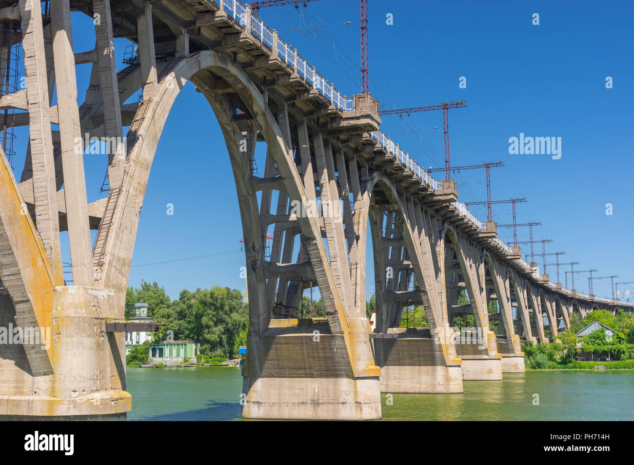 Sommer Landschaft mit einem alten Merefo-Hersonsky Bogenbrücke über Dnipro River im Zentrum der gleichnamigen Stadt, Ukraine Stockfoto