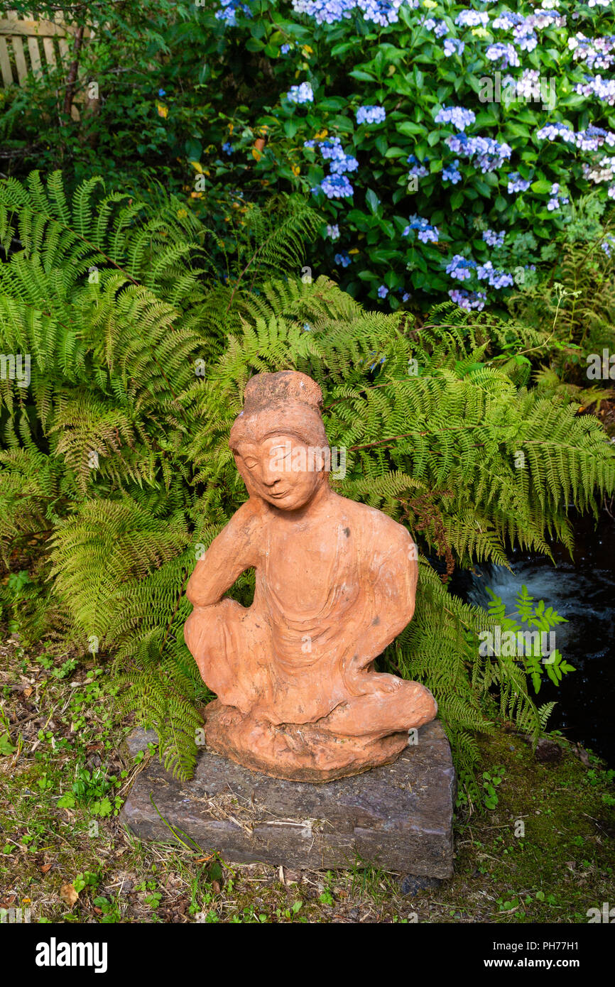 Kleine steinerne Figur von Buddha im Garten, Irland Stockfoto