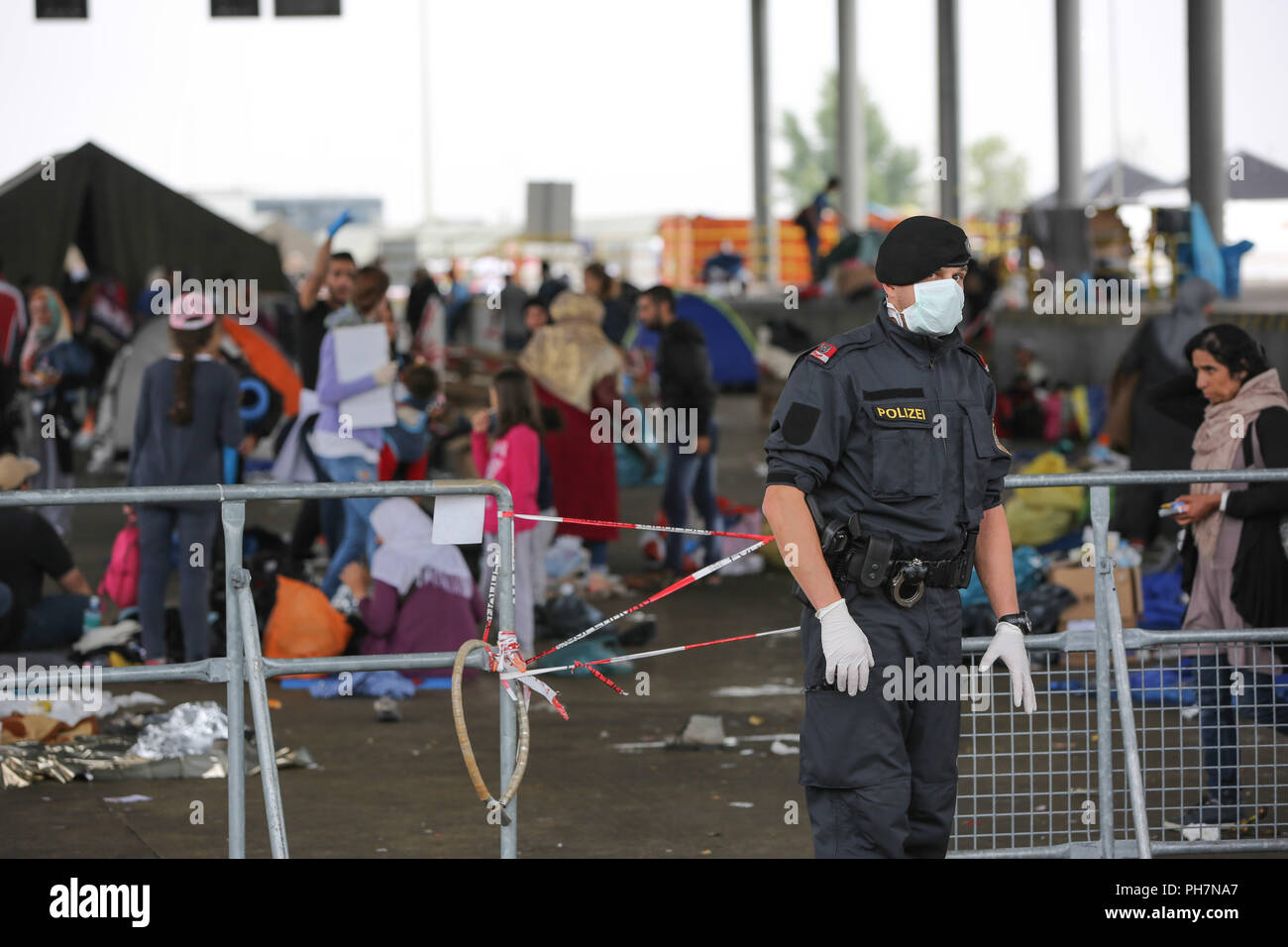 Nickelsdorf, Burgenland, Österreich. 15. Sep 2015. Ein Polizist ist mit einer Nase Abdeckung neben Flüchtlinge gesehen. Das österreichische Militär übernahm die Kontrolle über die Verwaltung von ankommenden Fluechtlinge an der österreichisch-slowenischen Grenzübergang Spielfeld. Sie wurden von den Christlichen NGO Caritas unterstützt. Die Flüchtlinge vor allem aus Syrien, Afghanistan und im Irak waren. Credit: Stanislav Jenis/SOPA Images/ZUMA Draht/Alamy leben Nachrichten Stockfoto