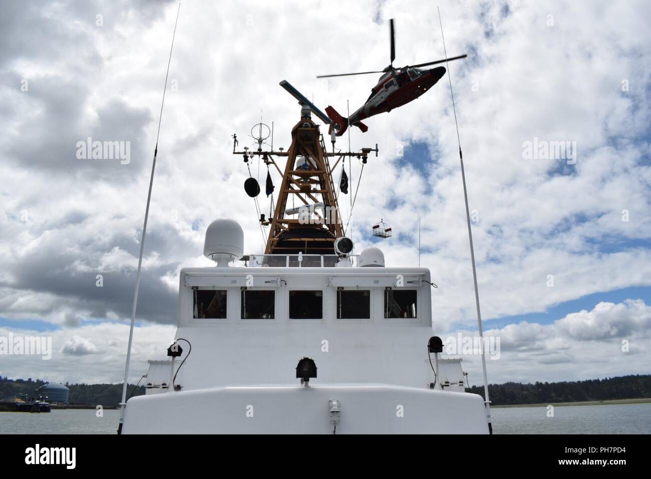 Einem MH-65 Dolphin Hubschrauber, von Sektor North Bend fliegt über das Patrouillenboot Orcas während einer Schulung Betrieb aus die Küste von Oregon, 30. Juni 2018. Ausbildung ist die tägliche Routine für alle Küstenwache an Bord alle Assets, die unsere Mannschaften bereit zu reagieren. Stockfoto