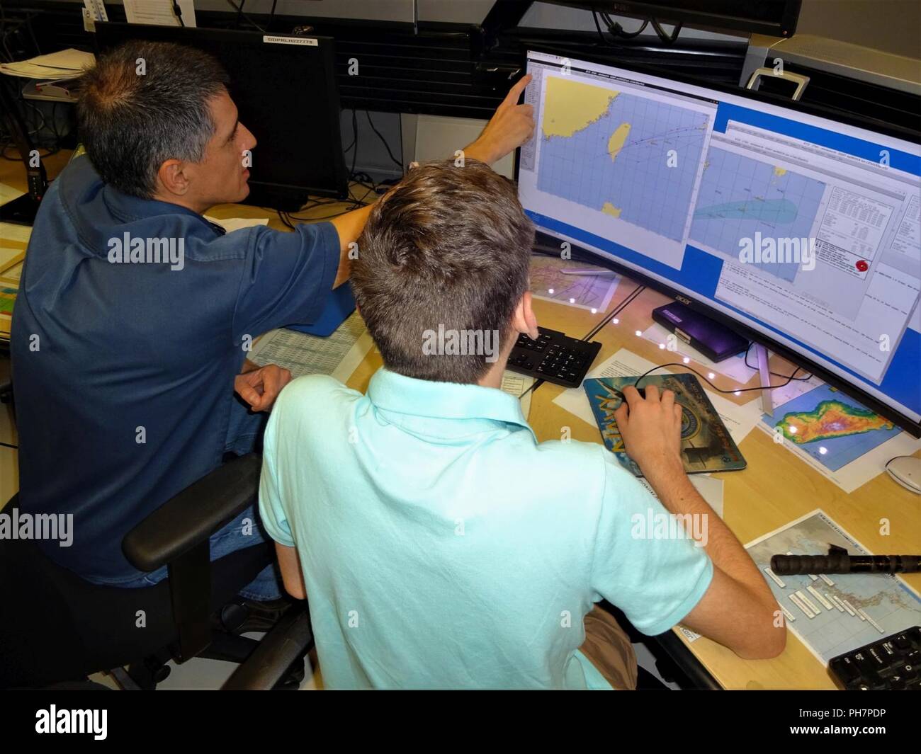 Herr Matt Kucas, Technical Services Department Head, erklärt, wie die Typhoon Offizier vom Dienst schafft tropischer Wirbelsturm Track, Intensität und wind Radien Prognosen mit verschiedenen Quellen von Satelliten- und Beobachtungsdaten, Modell und Daten. Stockfoto