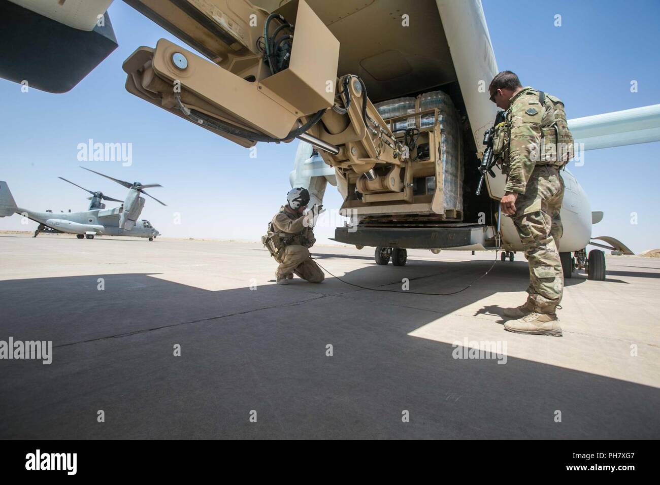 Irak (27. Juni 2018) eine US Marine Corps Crew Chief leitet ein Geländegängiges Lifter Armee System (ATLAS) II Gabelstapler Ladung in eine MV-22 Osprey B während einer Neuversorgung der Mission zur Unterstützung von Combined Joint Task Force - inhärenten Lösen (CJTF-OIR) am Flugplatz Qayyarah West, Irak, 27. Juni 2018 zu laden. CJTF-OIR ist der militärische Arm der Globalen Koalition zu besiegen ISIS in ausgewiesenen Teile des Irak und Syrien. Stockfoto